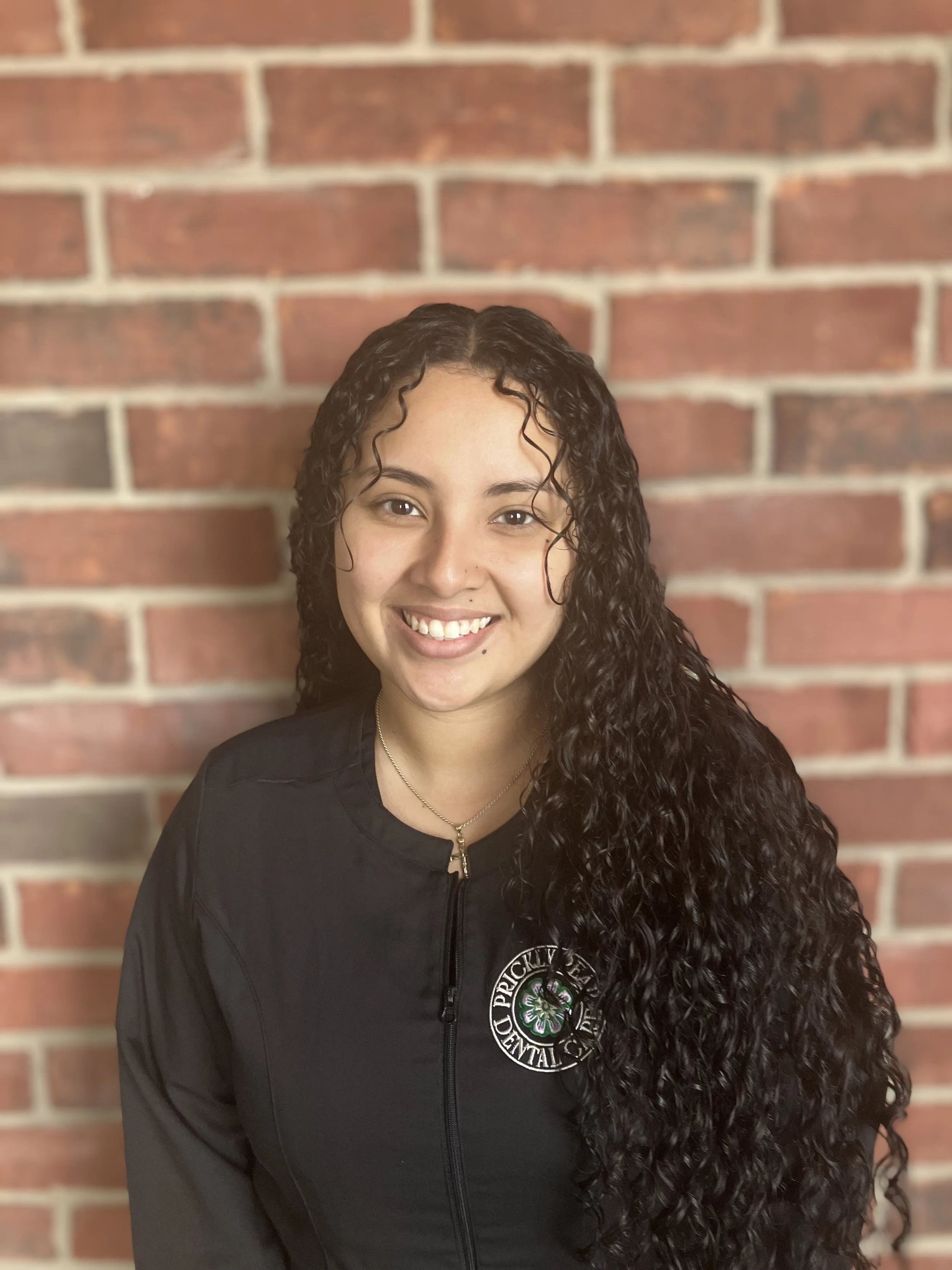 A photo of Soreli in front of the brick wall in the waiting room of Prickly Pear Dental Care.