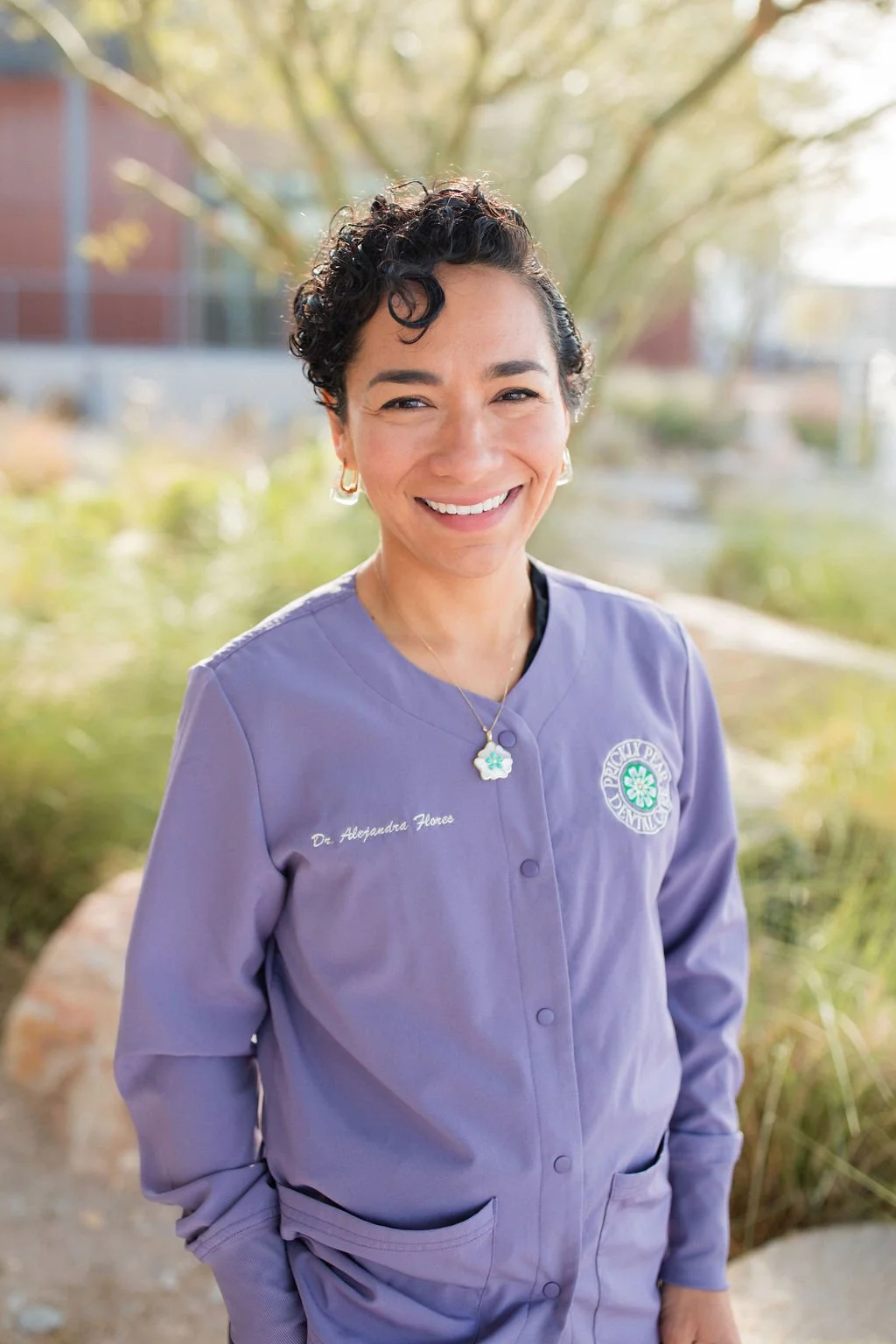 A portrait-style photo of Dr. Alejandra Flores Arellano, taken in the outdoor space adjacent to Prickly Pear Dental Care.