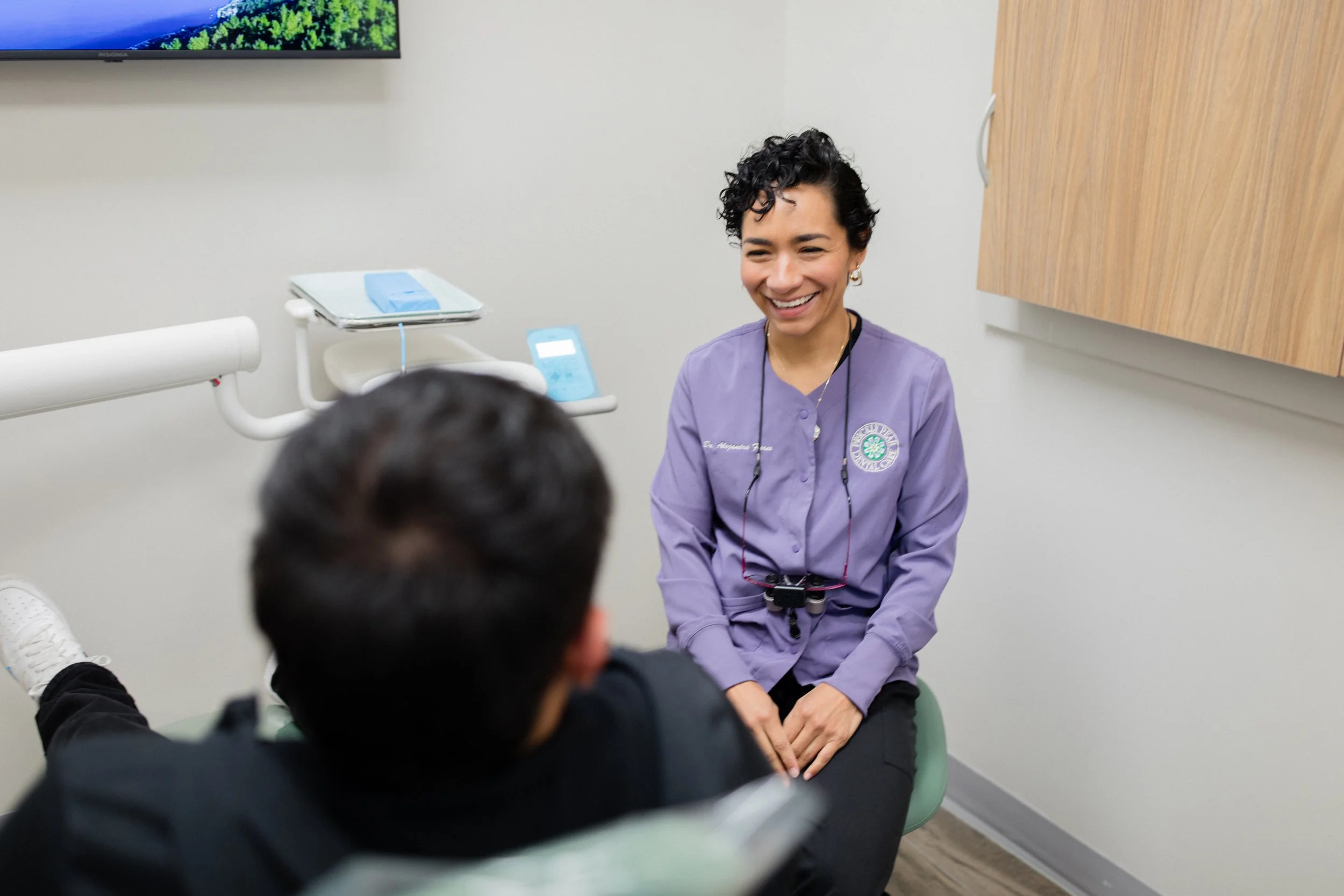 An image of Dr. Flores from Prickly Pear Dental Care smile at a patient seated in a dental chair.