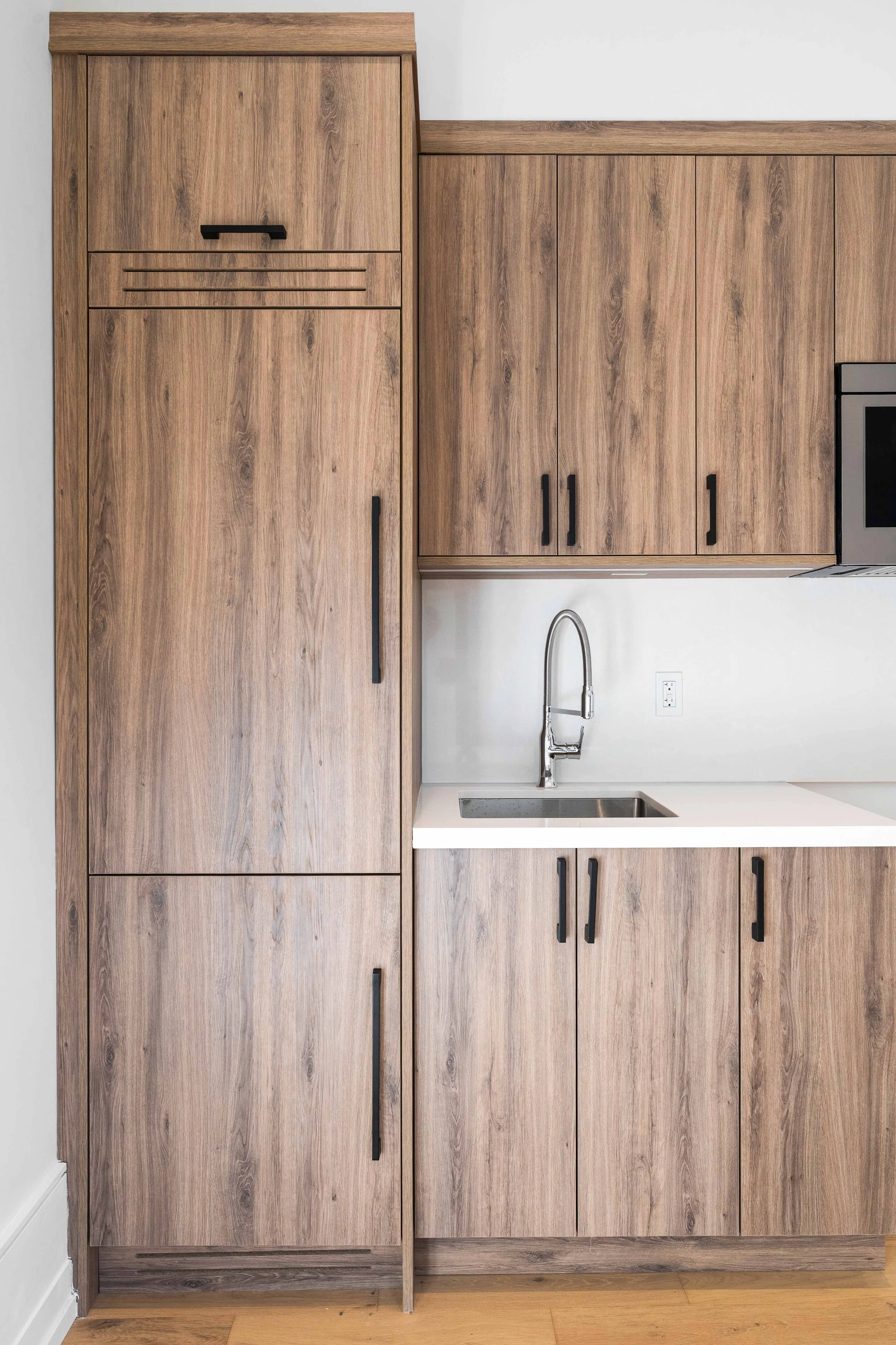 Kitchen with wooden cabinets, a white countertop, a stainless steel sink with a high-arc faucet, and a microwave.