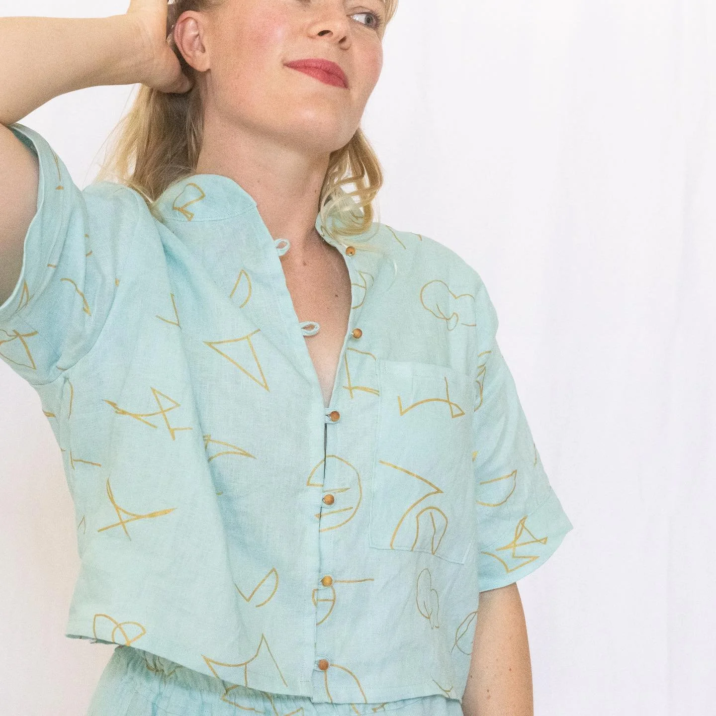 Sacred Details
Our cropped *Zeal Shirt in Glacier* is finished with sandalwood bead buttons &mdash; grounding, fragrant, and spiritually potent.

Each one is a prayerful touch, pairing with organic linen and hand-drawn Light Language to create wearab