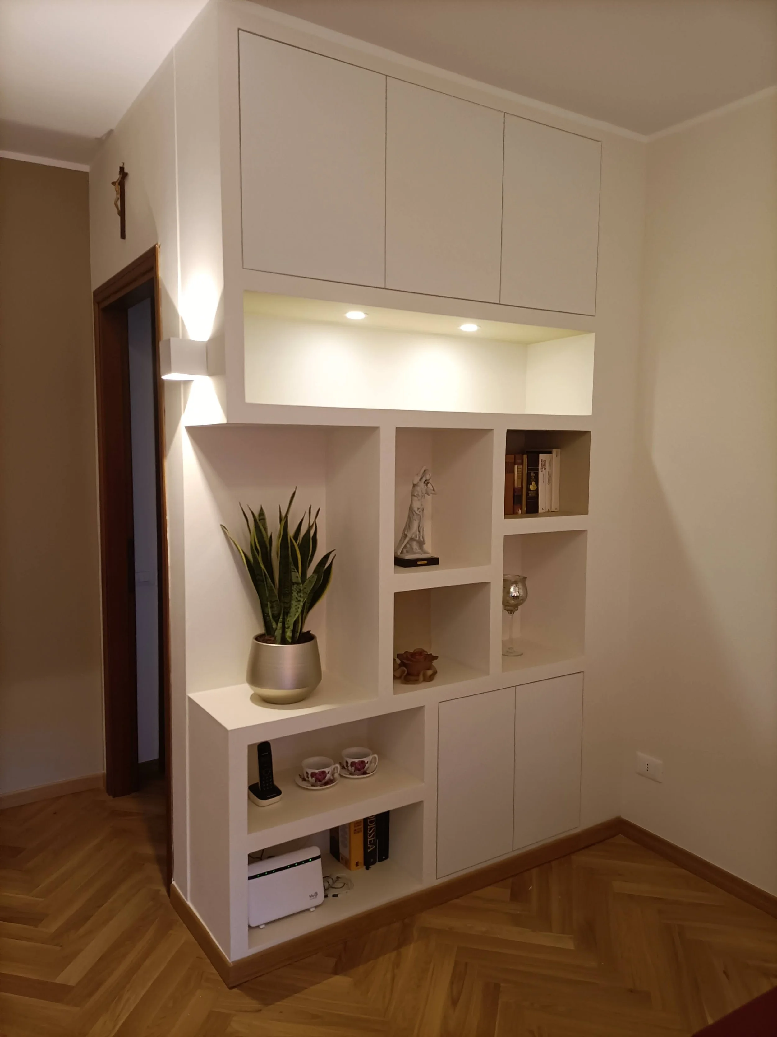 Libreria in cartongesso su misura con sportelli a filo verniciabili, realizzati per creare nicchie decorative e vani contenitivi perfettamente integrati con l'arredo. 