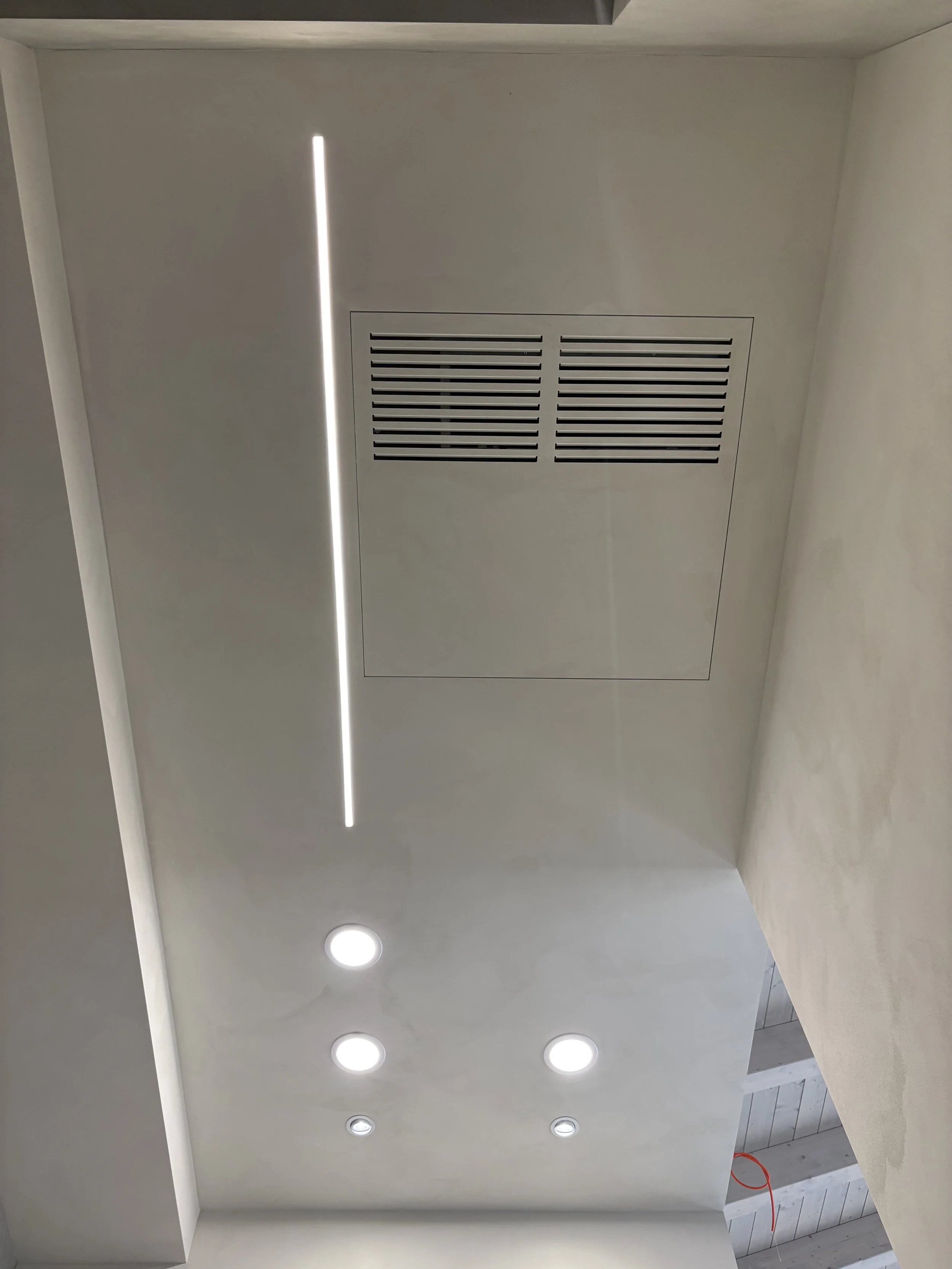 Botola filo muro a soffitto con faretti LED incassati e linea luminosa integrata.