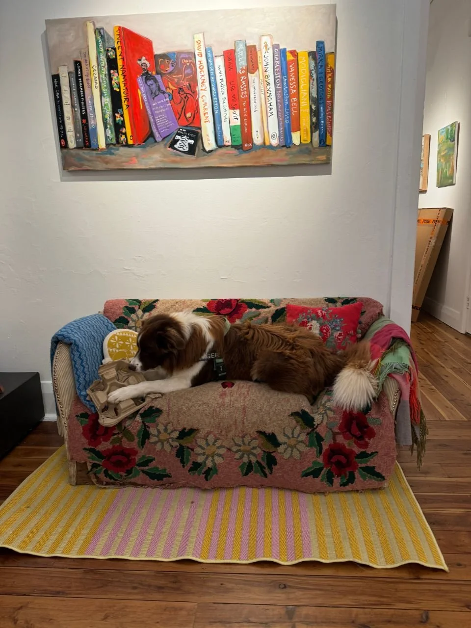 A dog on a lounge in an art gallery.