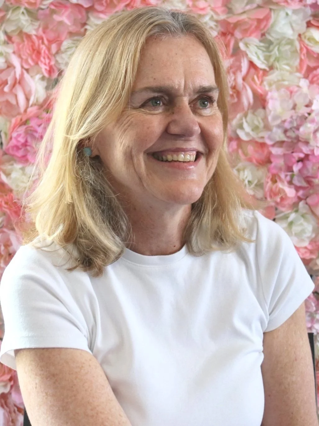 Smiling woman in a white shirt with a floral background.