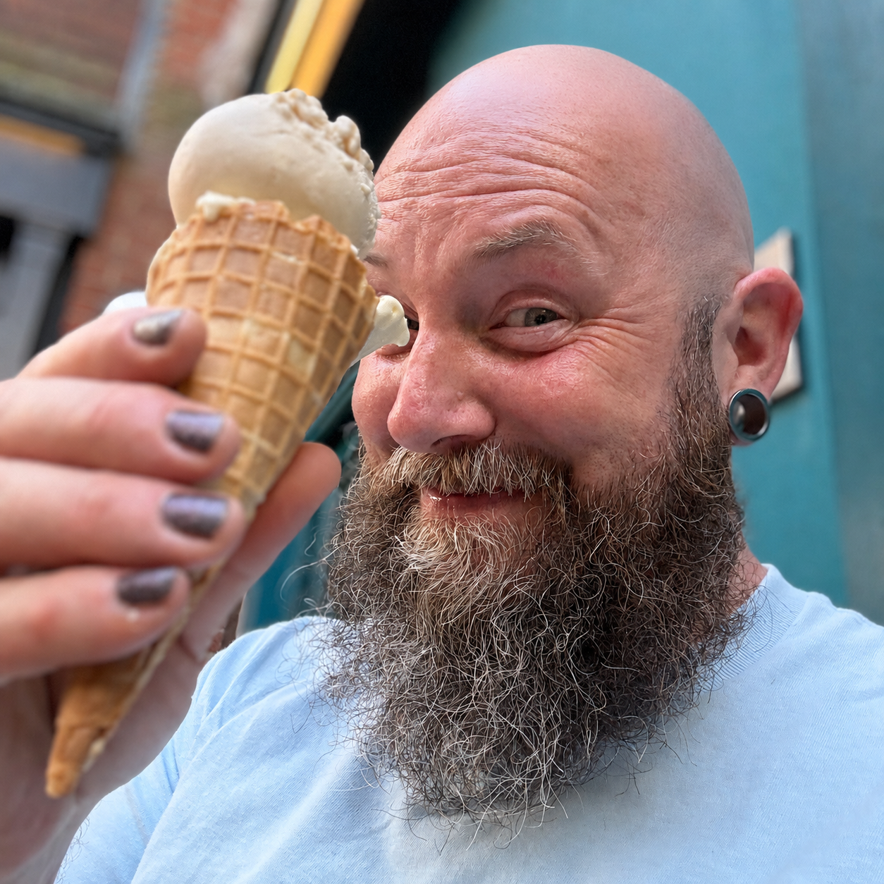 Queer therapist smiling while holding an ice cream cone outdoors