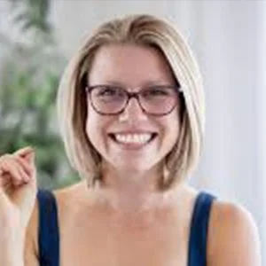 Smiling woman with glasses and shoulder-length blonde hair in a blue tank top