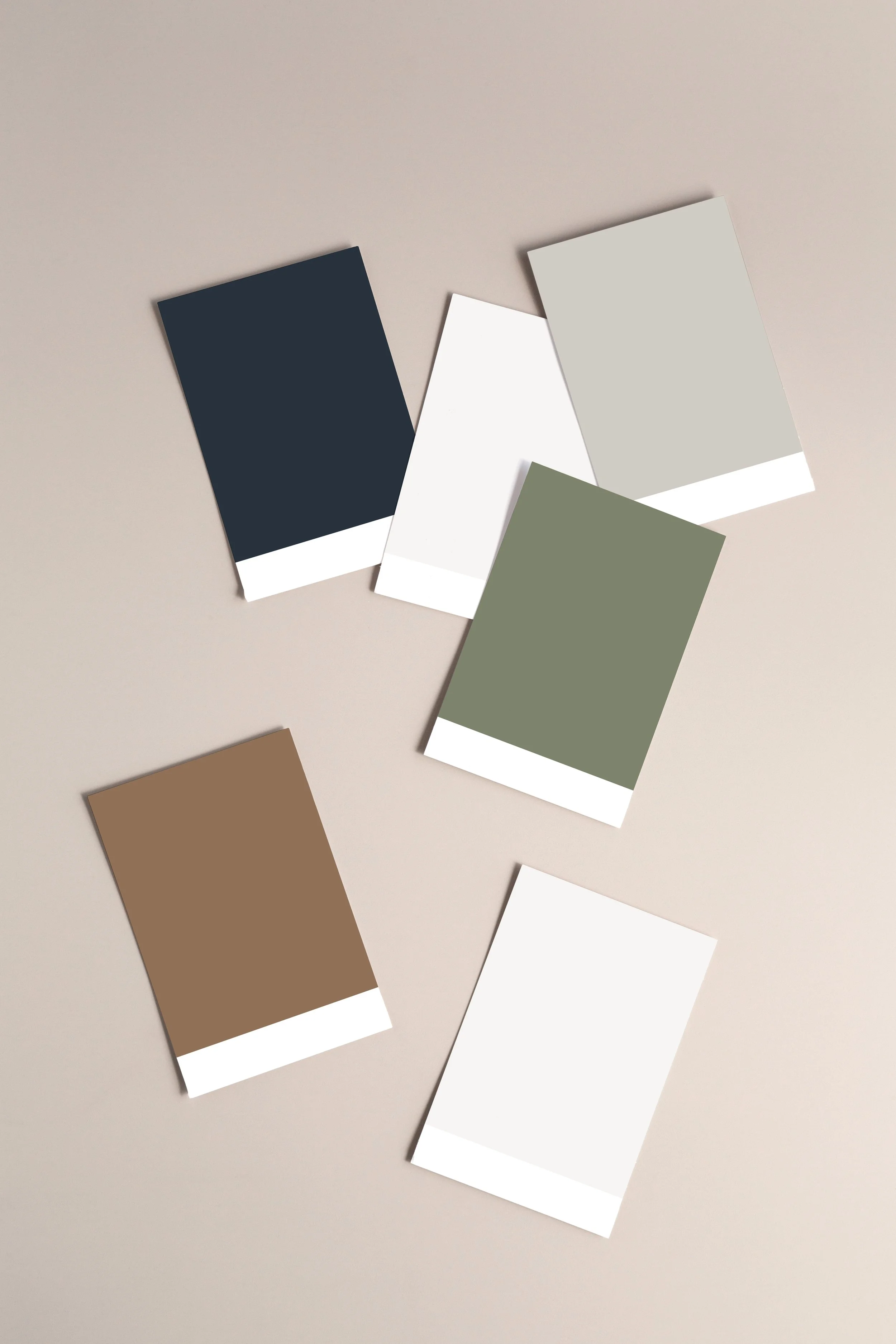 Six color swatch cards in navy, white, light gray, olive, beige, and white laid out on a beige surface.