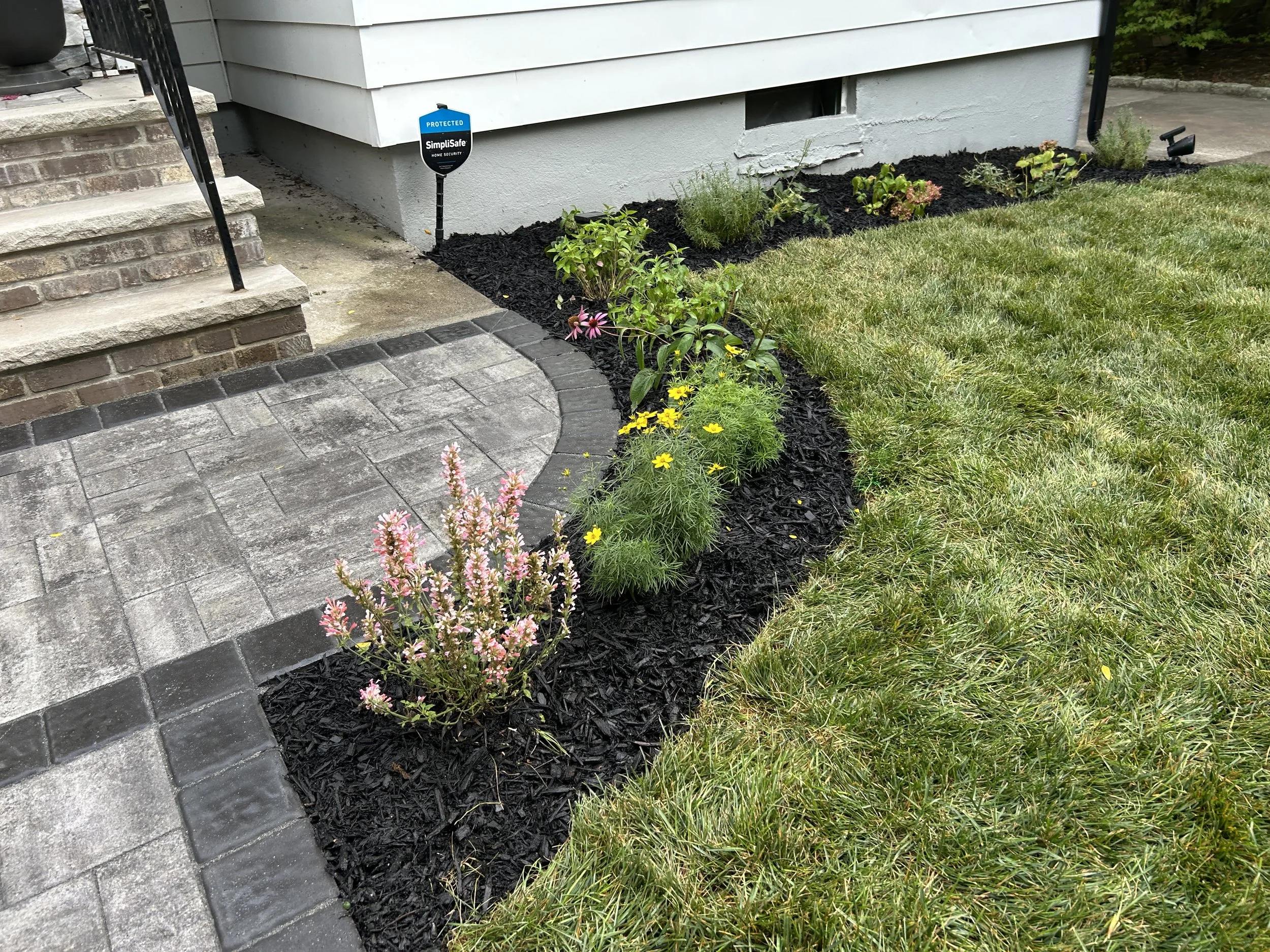 Front yard with flower bed, walkway, and steps leading to the house entrance.