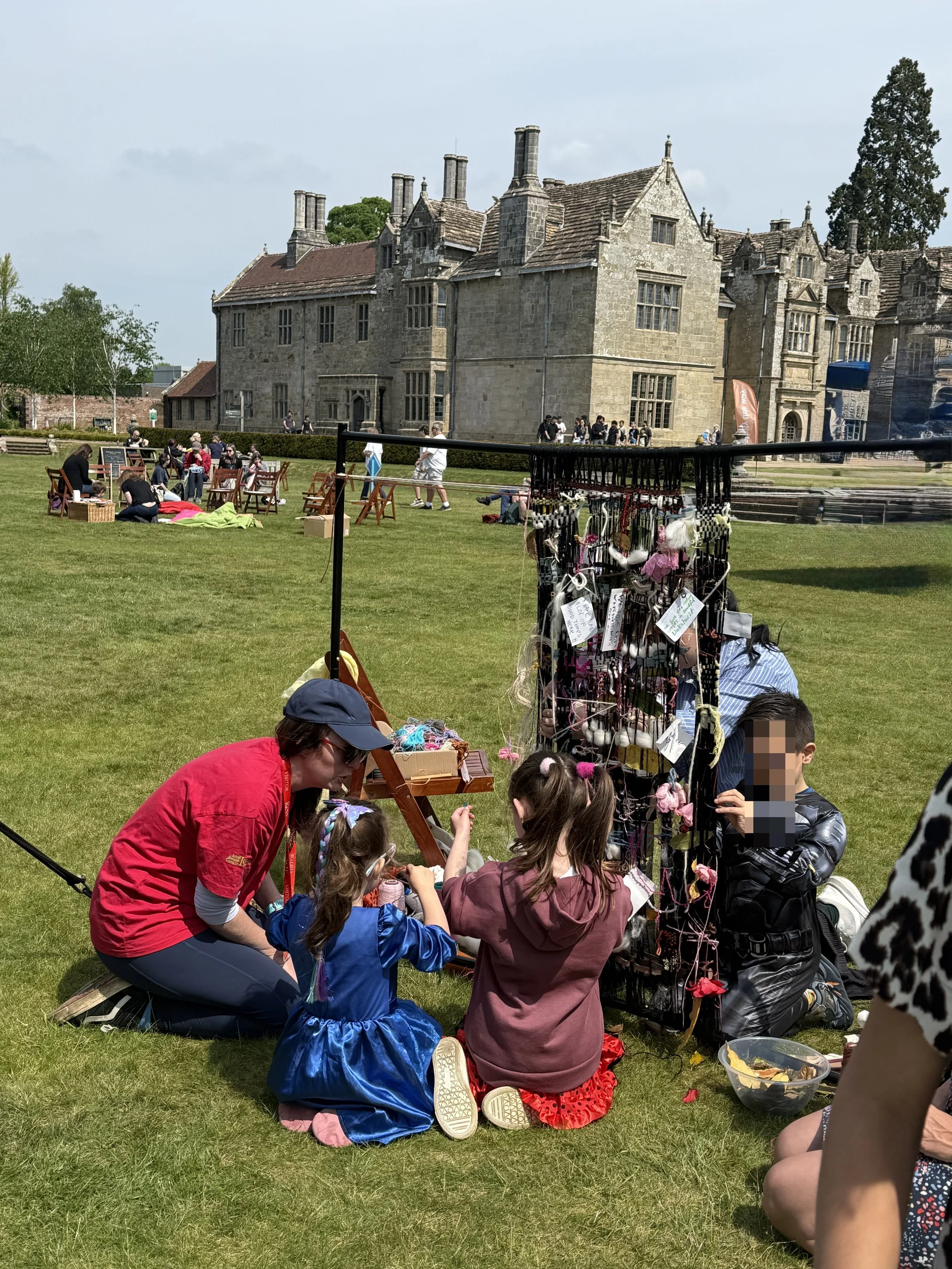 Families and children taking part in a community weaving activity facilitated by Peel Studio at Kew Wakehurst Community Festival
