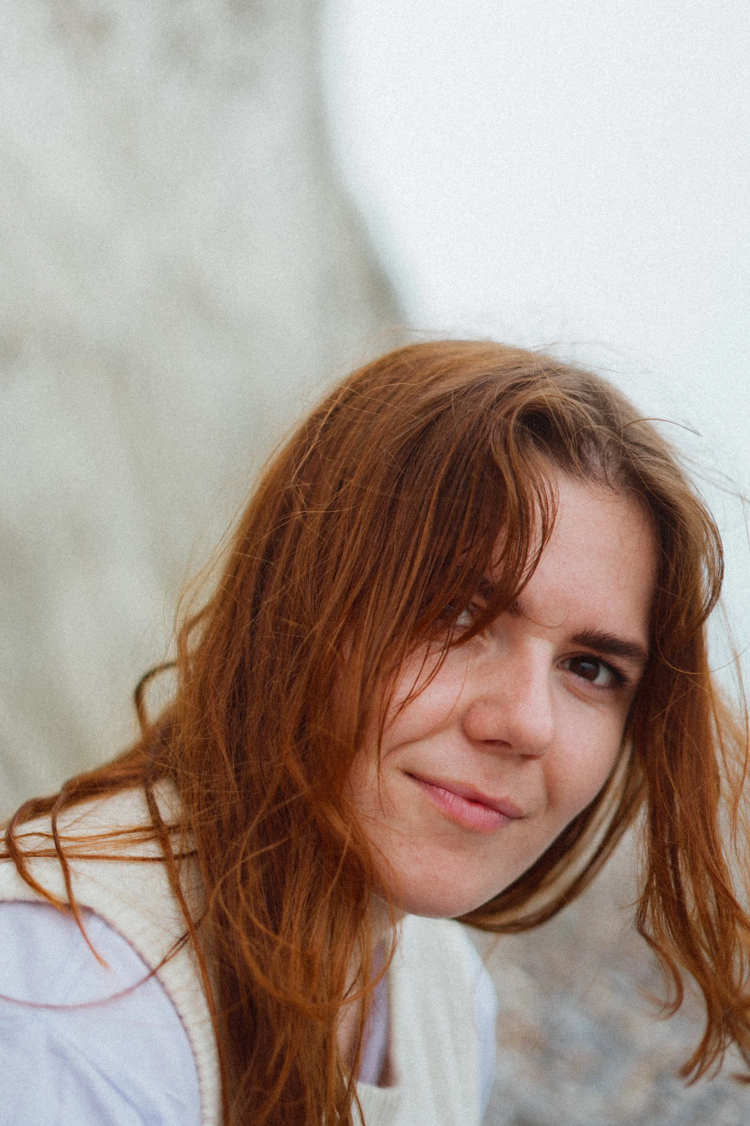 Portret van een jonge vrouw met rood haar die naar de camera kijkt.