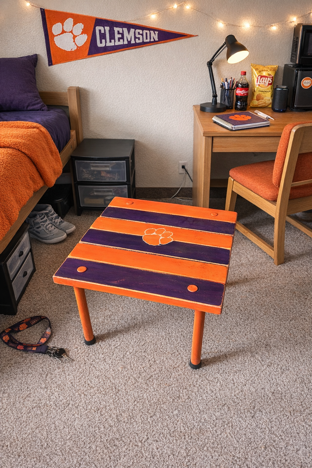 Clemson roll-out table in a dorm room, orange and purple striped portable cedar table with Clemson paw logo used as a compact student side table