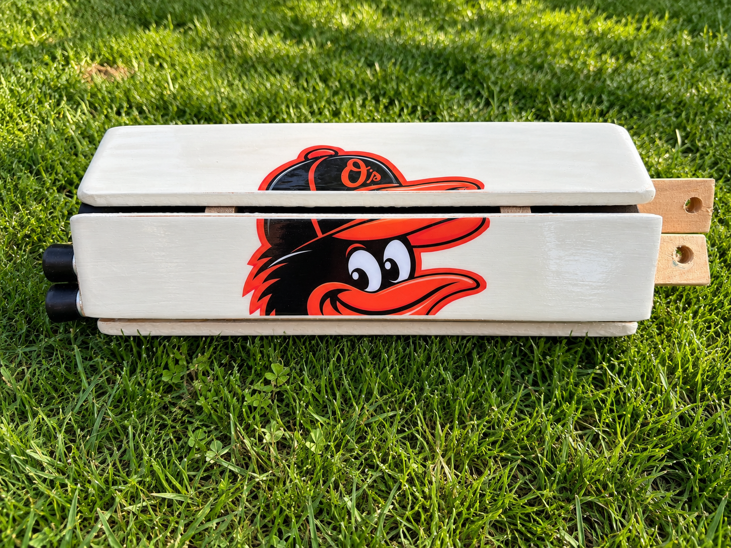 Folded Orioles Cornhole Board on Grass.png