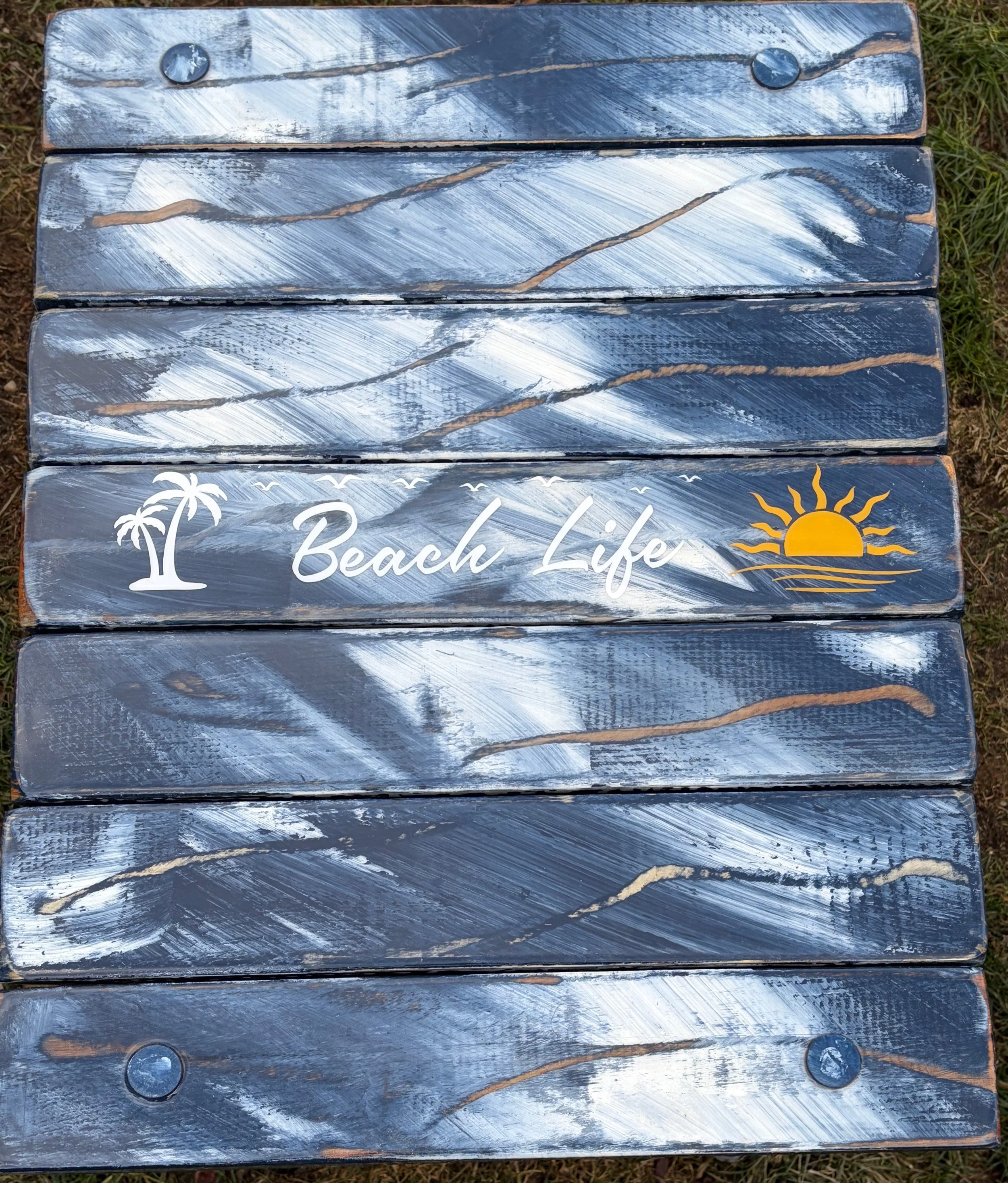 a close up view of a denim blue table with words Beach Life on a sandy beach