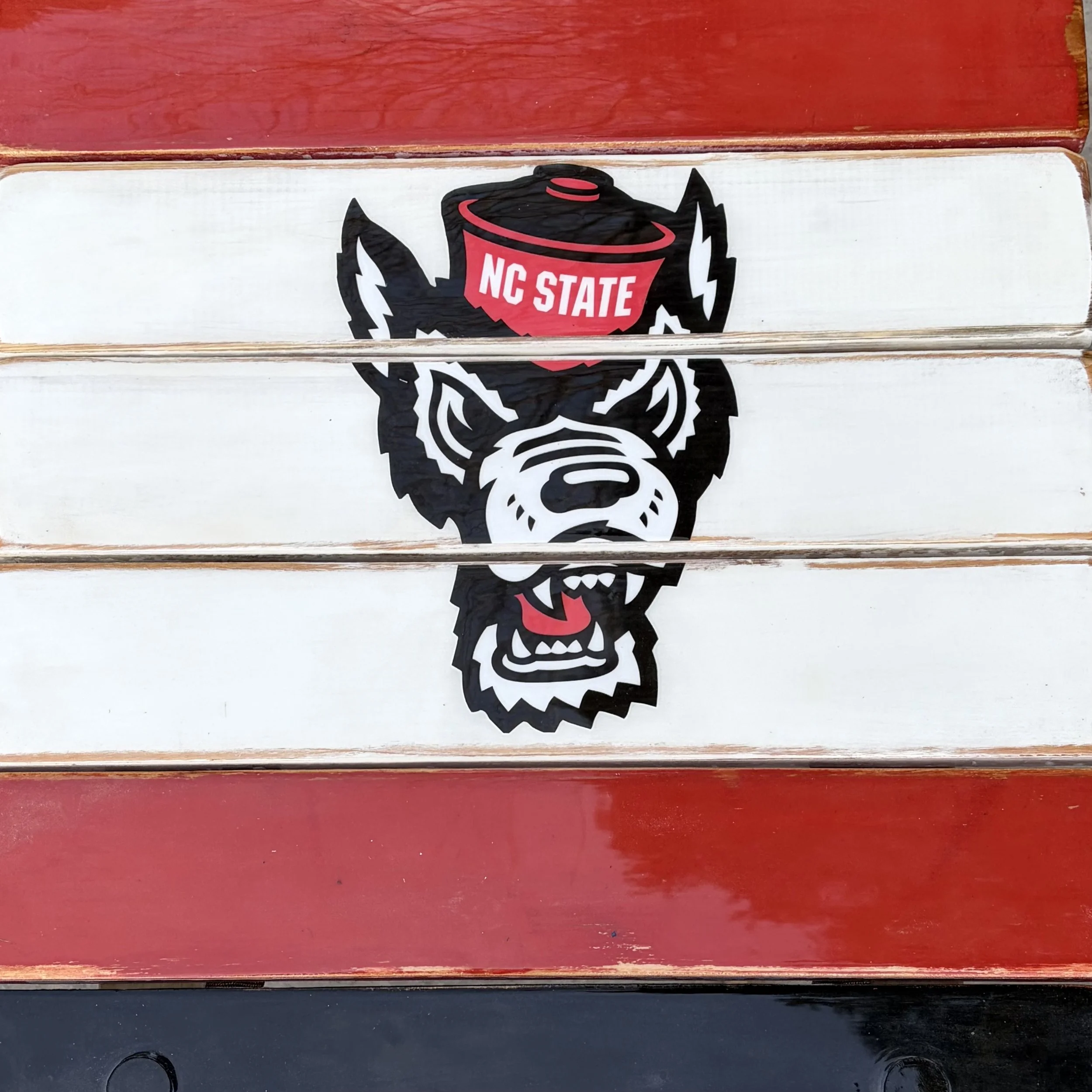 Close-up of NC State roll-out table featuring red, white, and black boards with wolf logo