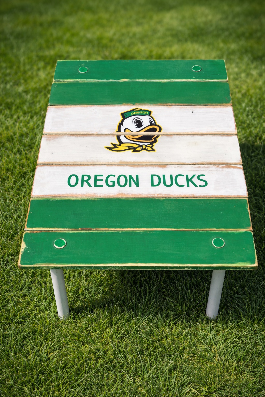 Custom Oregon Ducks roll-out table displayed on green grass, handcrafted cedar university table in green and white