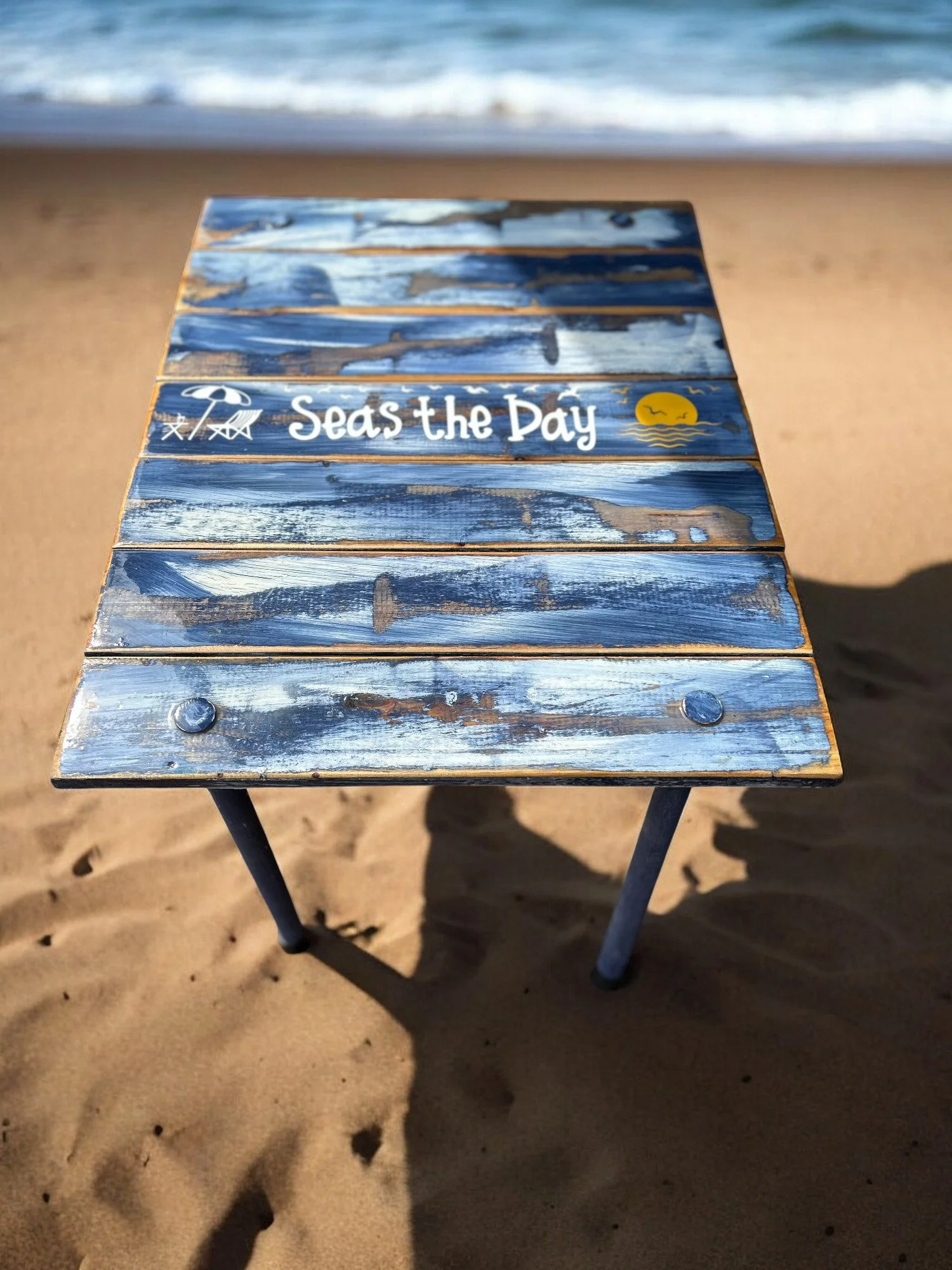 a roll up beach table in a bag with the saying seas the day on the shoreline of a beach