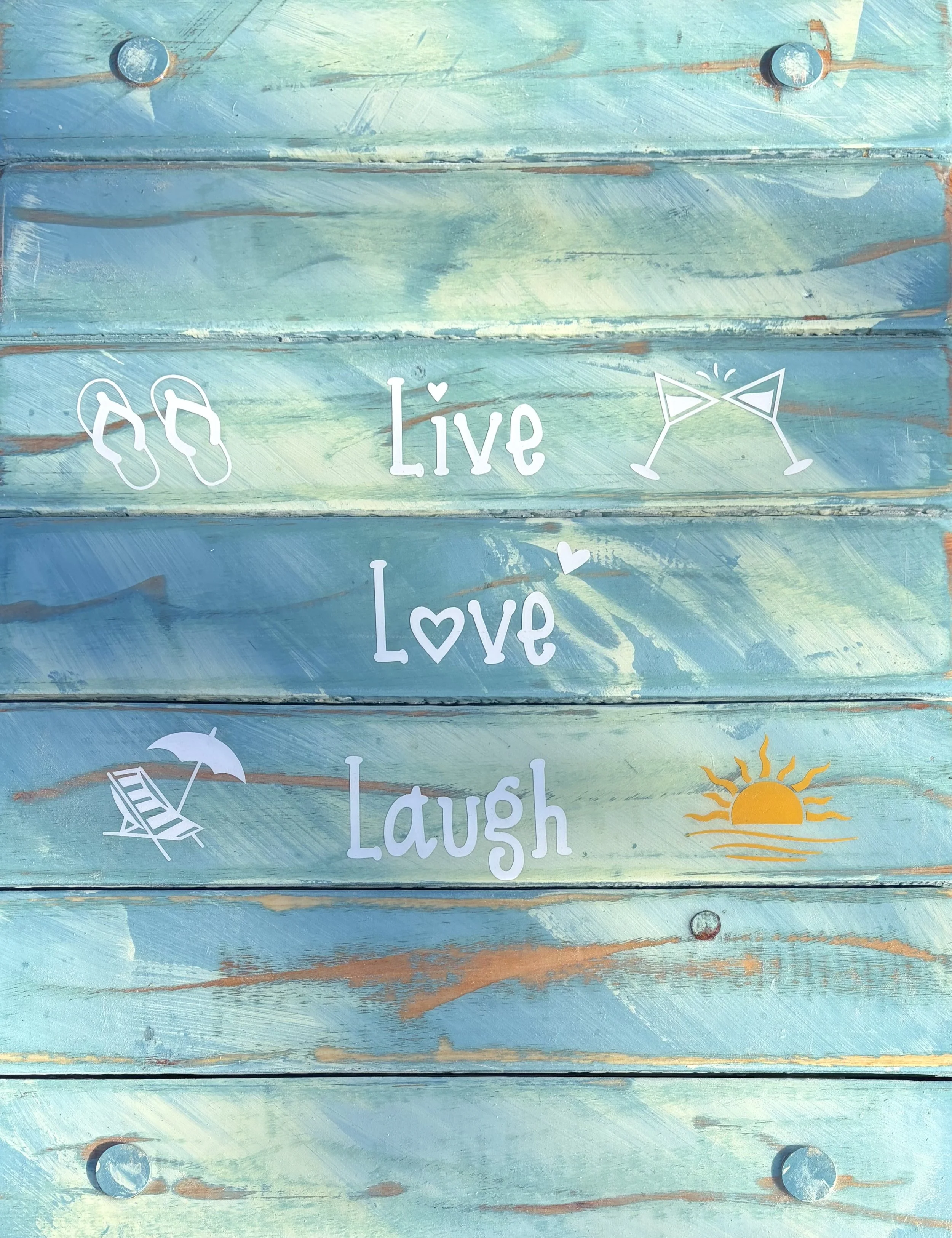 a close up of a  turquoise beach table that says live love laugh on the beach next to two beach chairs