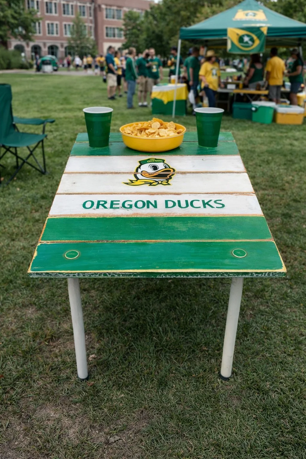 Oregon Ducks roll-out table set up on campus during a college tailgate, custom cedar university table with green and white design