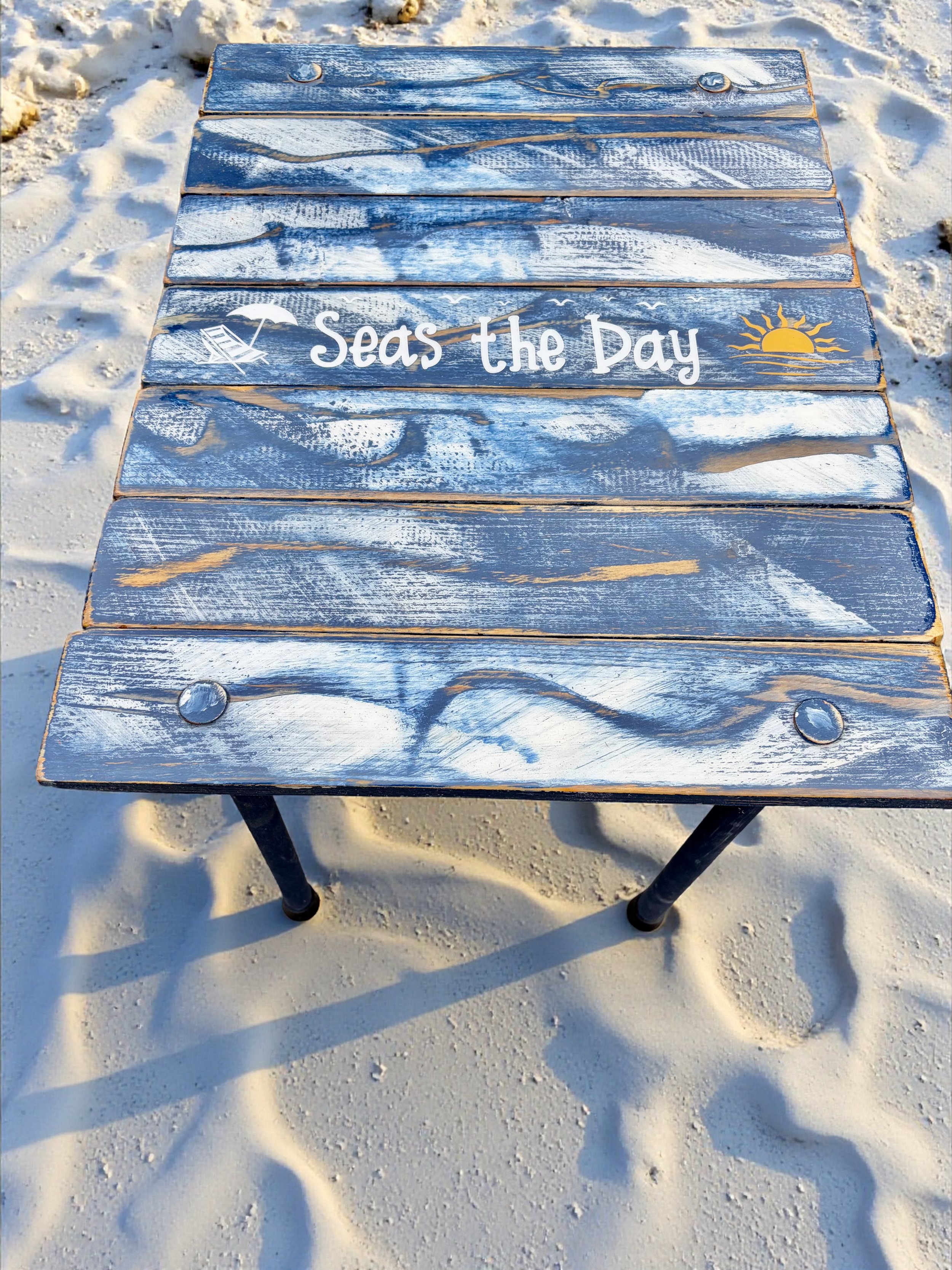 a roll up beach table in a bag with the saying seas the day on a white sandy beach
