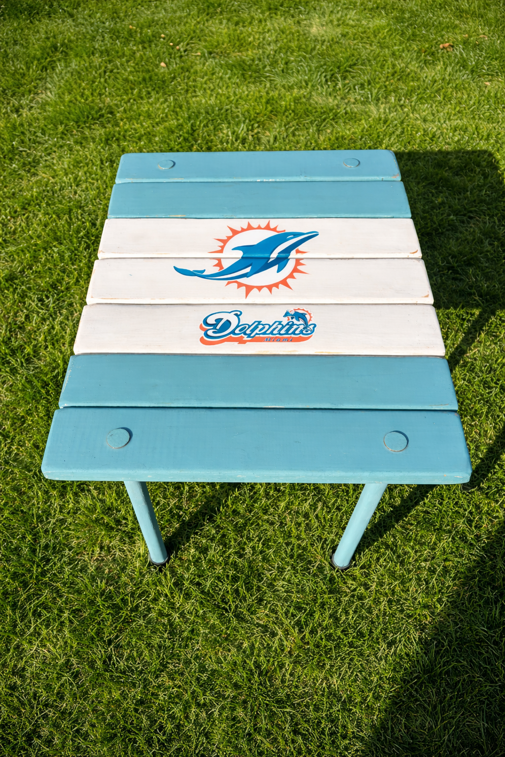 Miami Dolphins roll-out table on green grass, handcrafted cedar wood portable table for tailgating and outdoor use