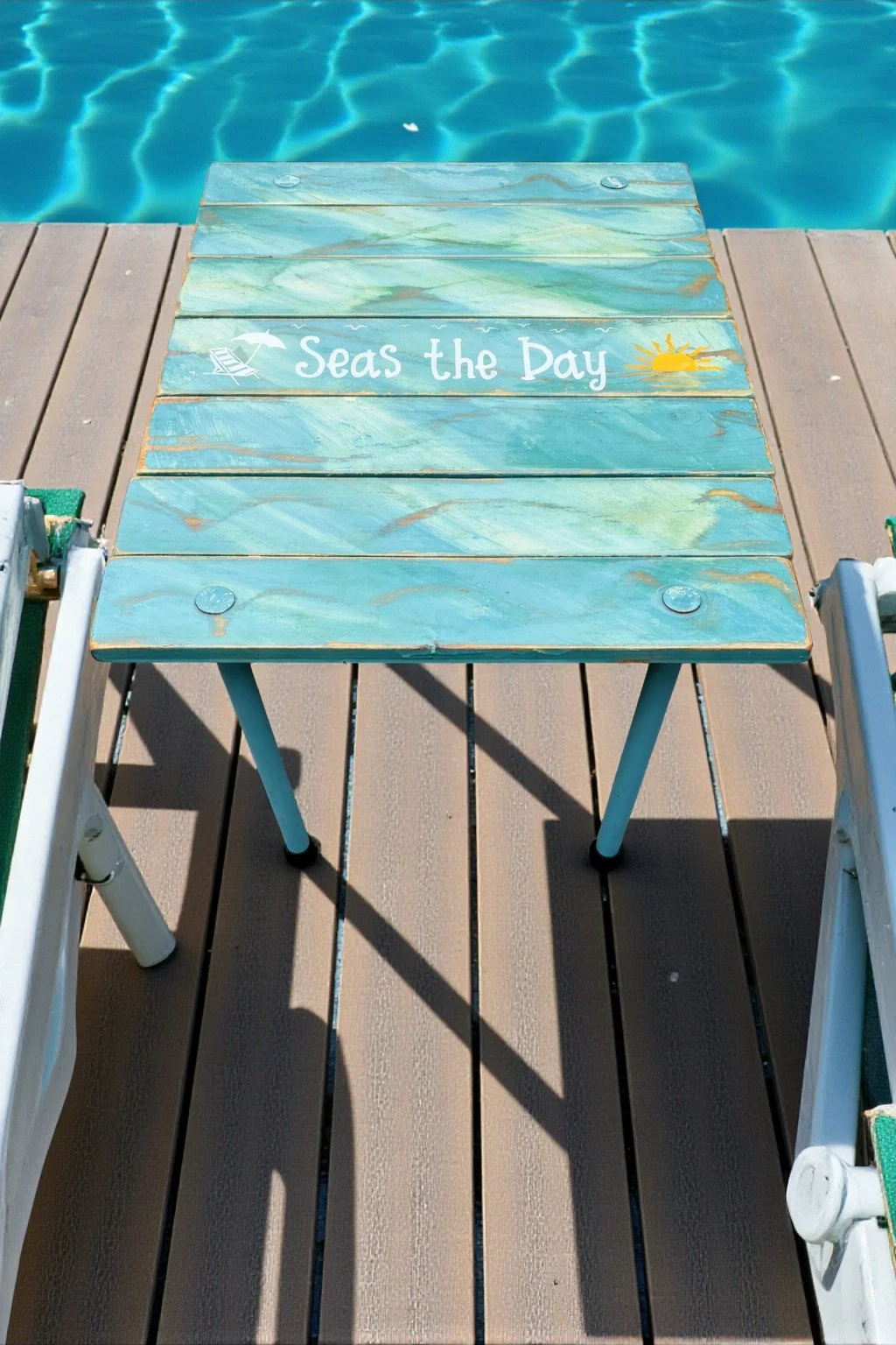 a turquoise beach table that rolls up and says seas the day next to a pool