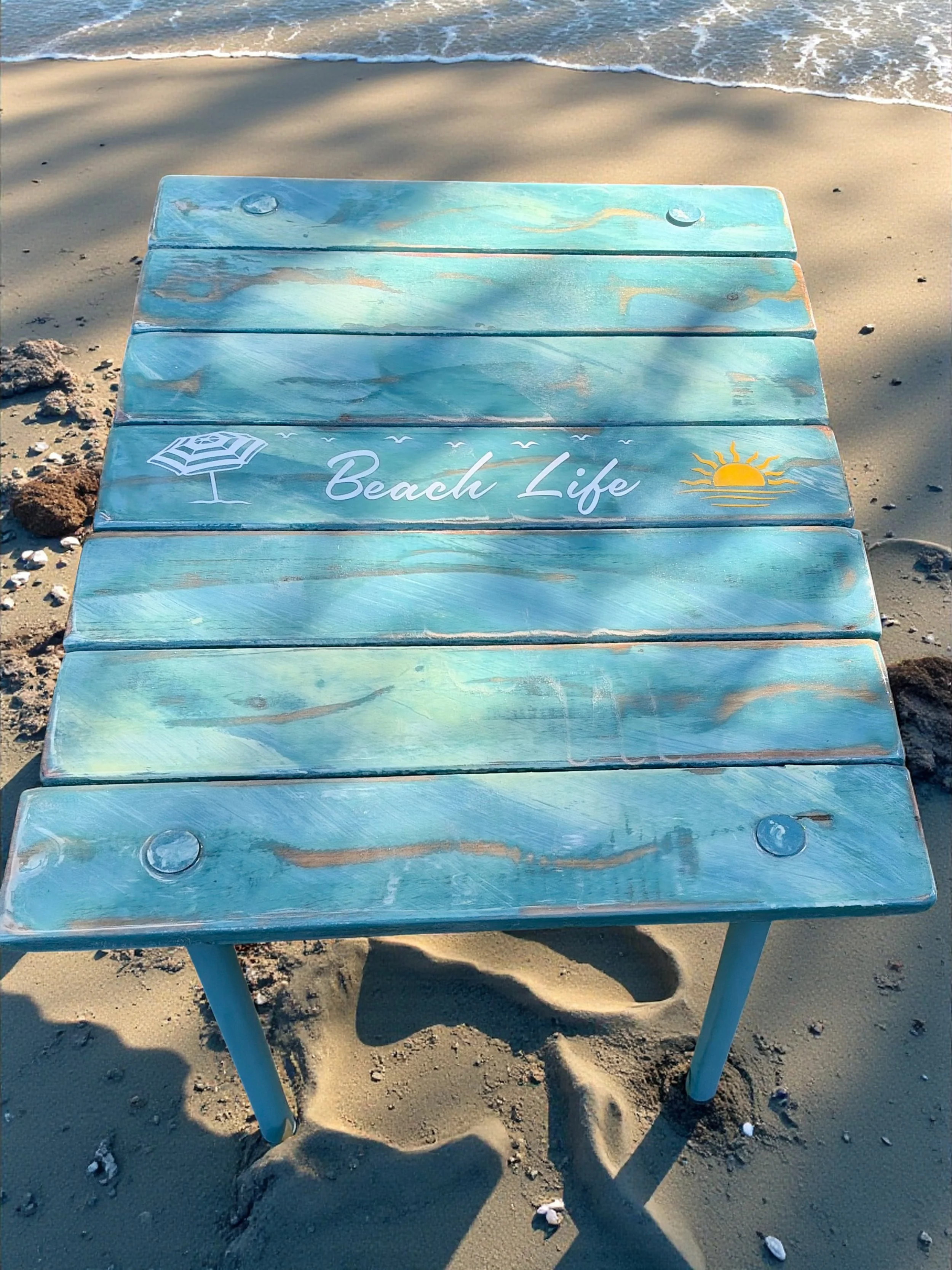 a turquoise beach table that says beach life on a sandy beach