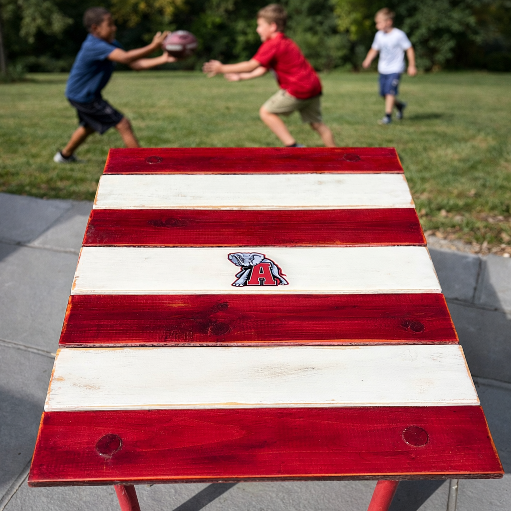 Handmade Alabama roll-out table in a bag with red and white cedar boards, shown outdoors on a patio with boys playing football in the background