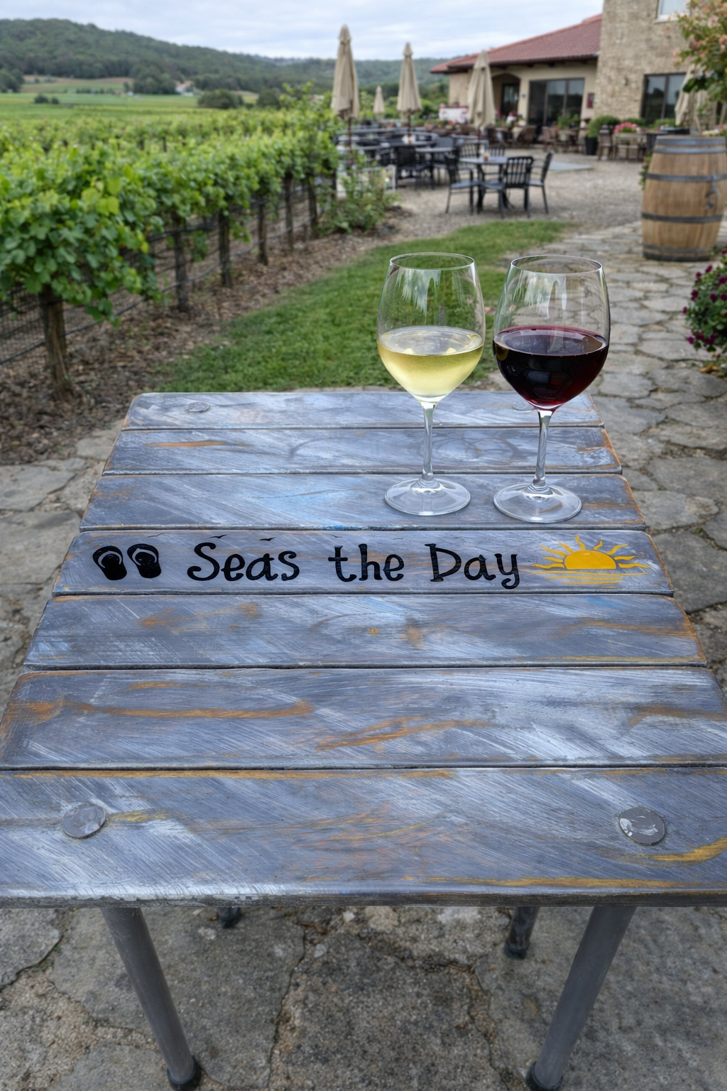 a gray whitewash beach table in a bag with the saying seas the day at a winery with two glasses of wine