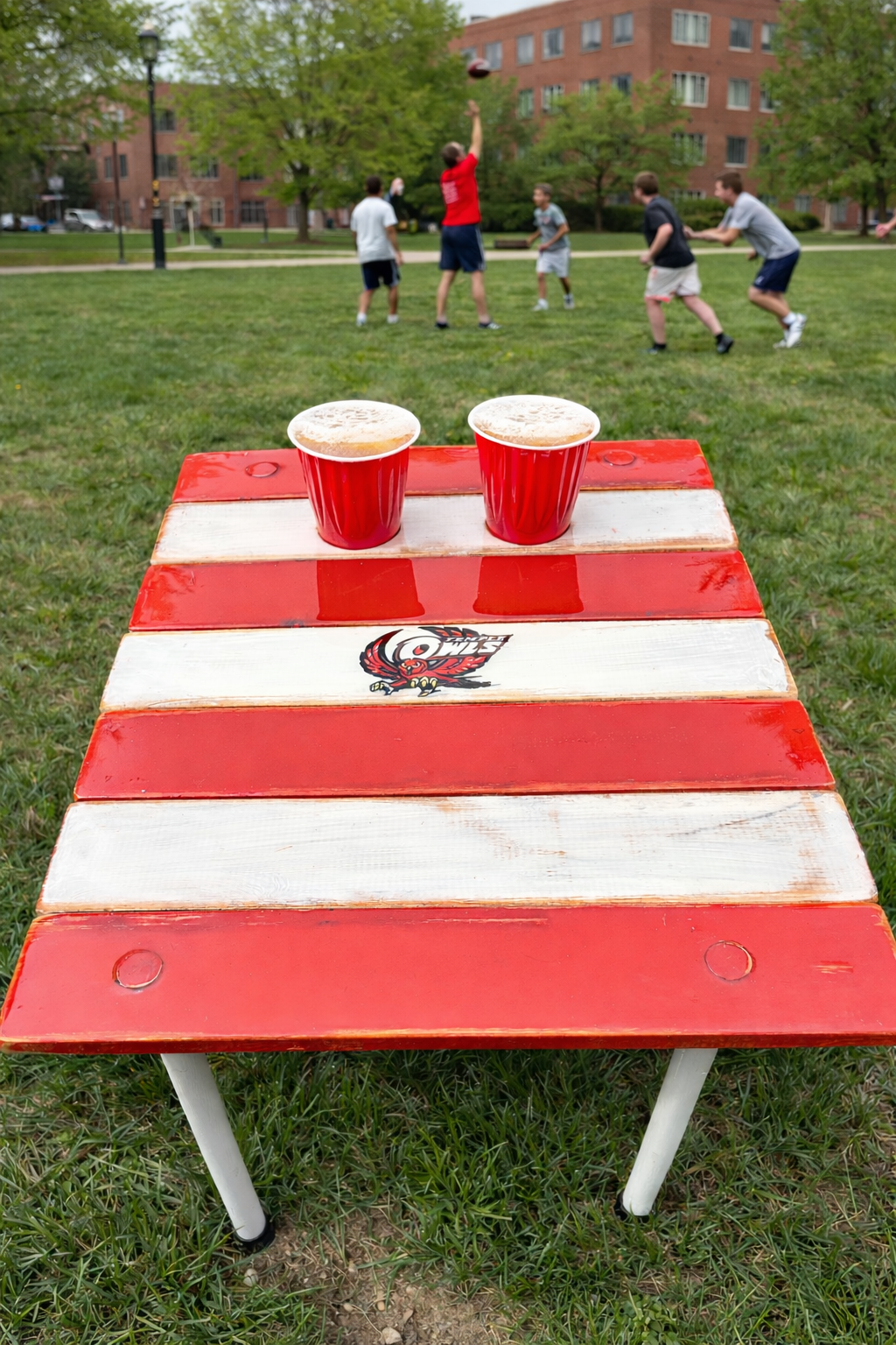Temple Owls roll-out table in a bag with red cups on college campus lawn during football game