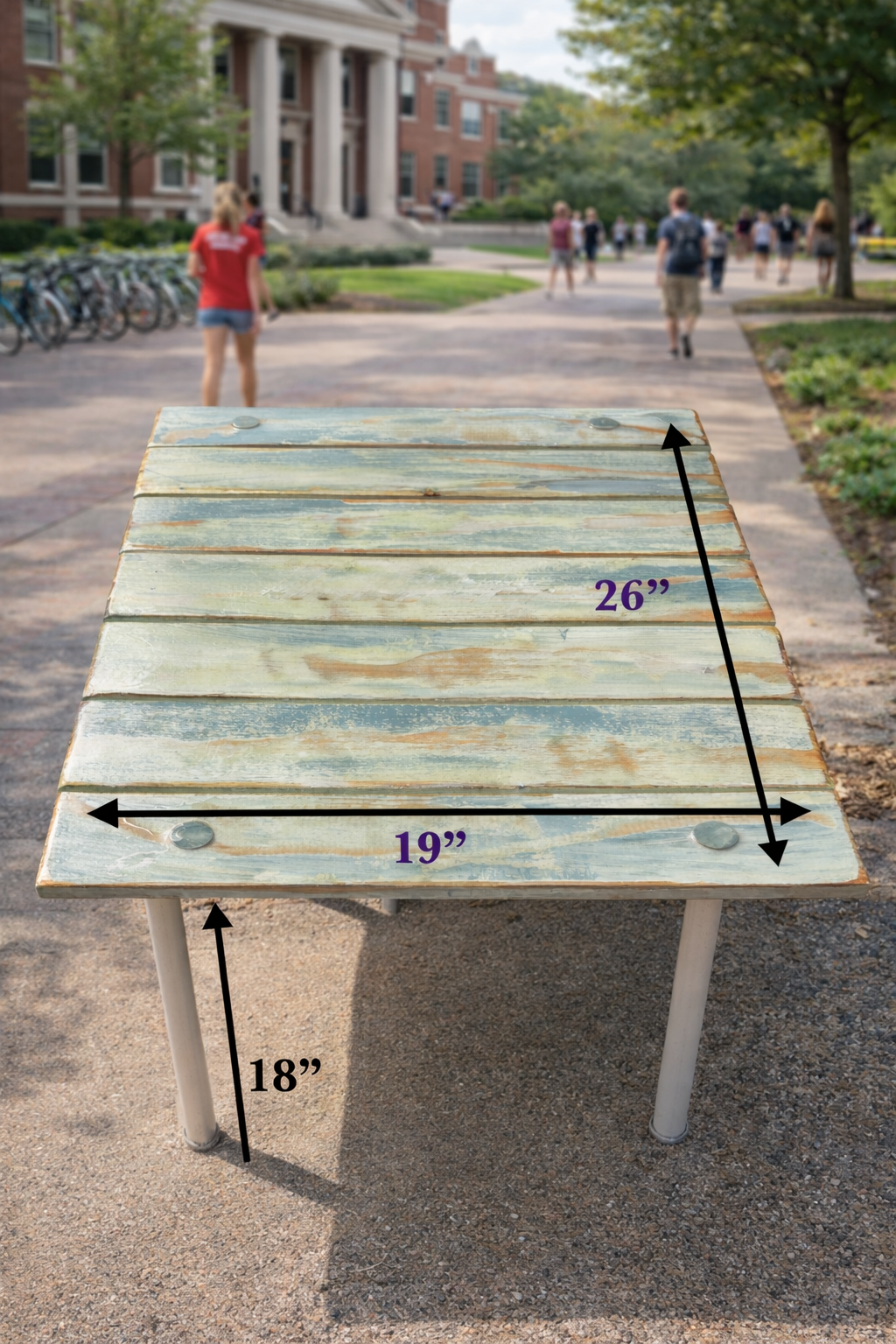 Portable roll-out table with dimensions shown, displayed on a college campus walkway (Copy)