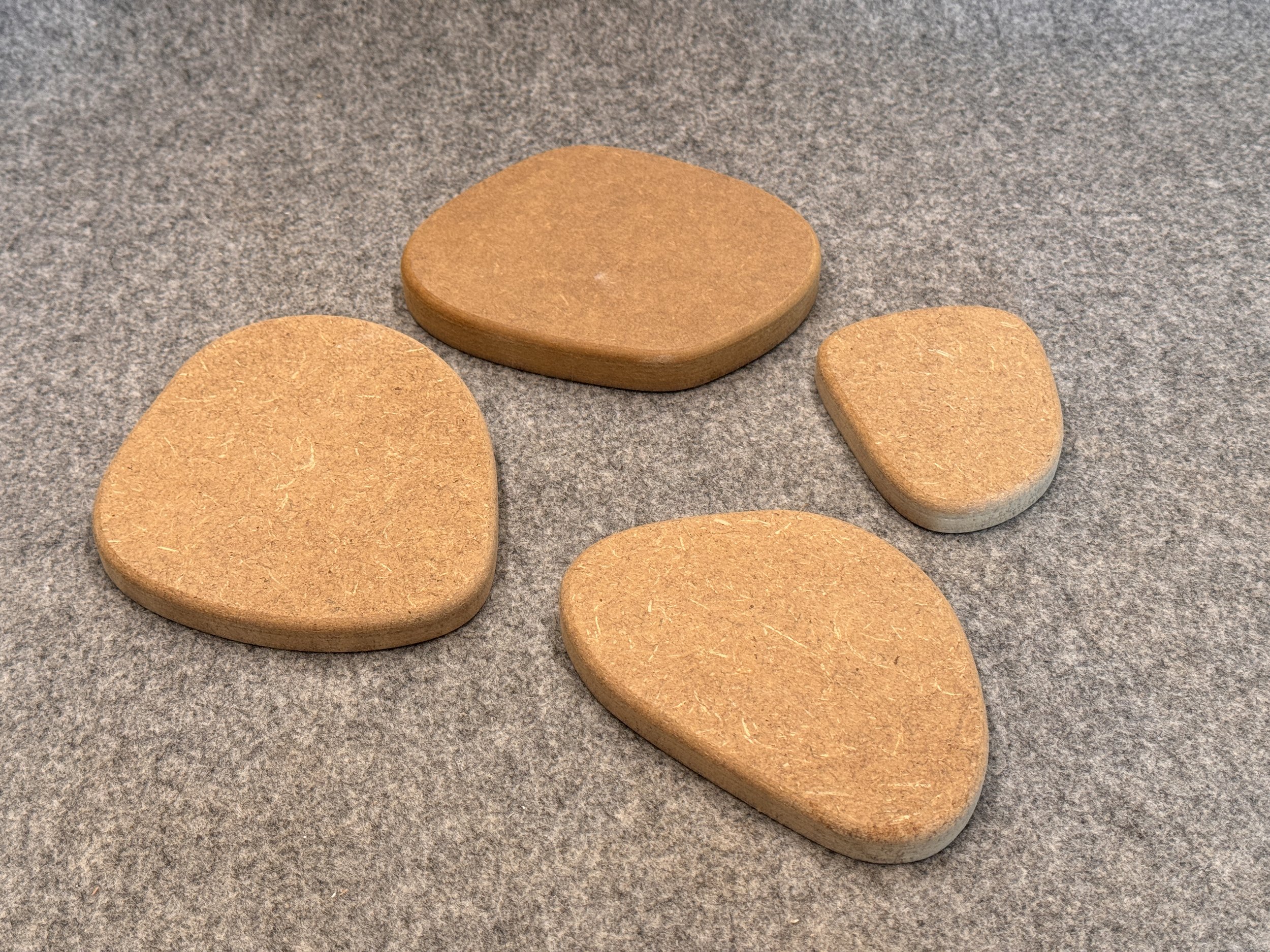 Vier unterschiedlich große, runde und ovale, braune Steine auf grauem Filz.