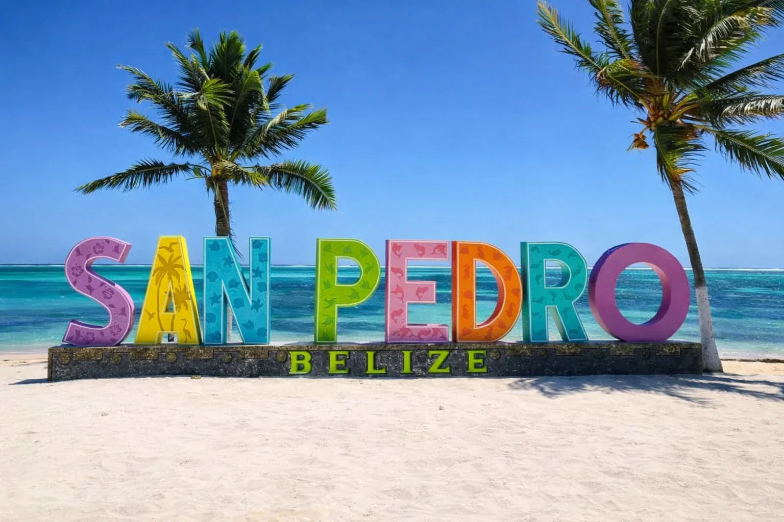 Colorful San Pedro Belize sign on the beach with palm trees and Caribbean Sea