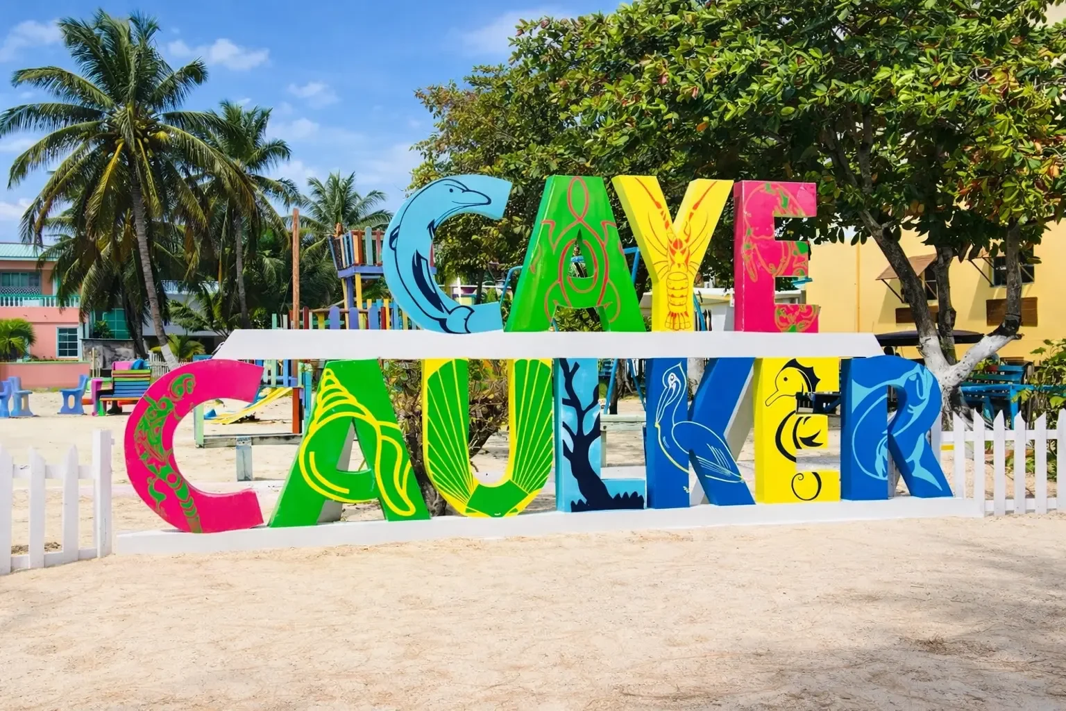 Colorful Caye Caulker Belize sign on the beach surrounded by palm trees