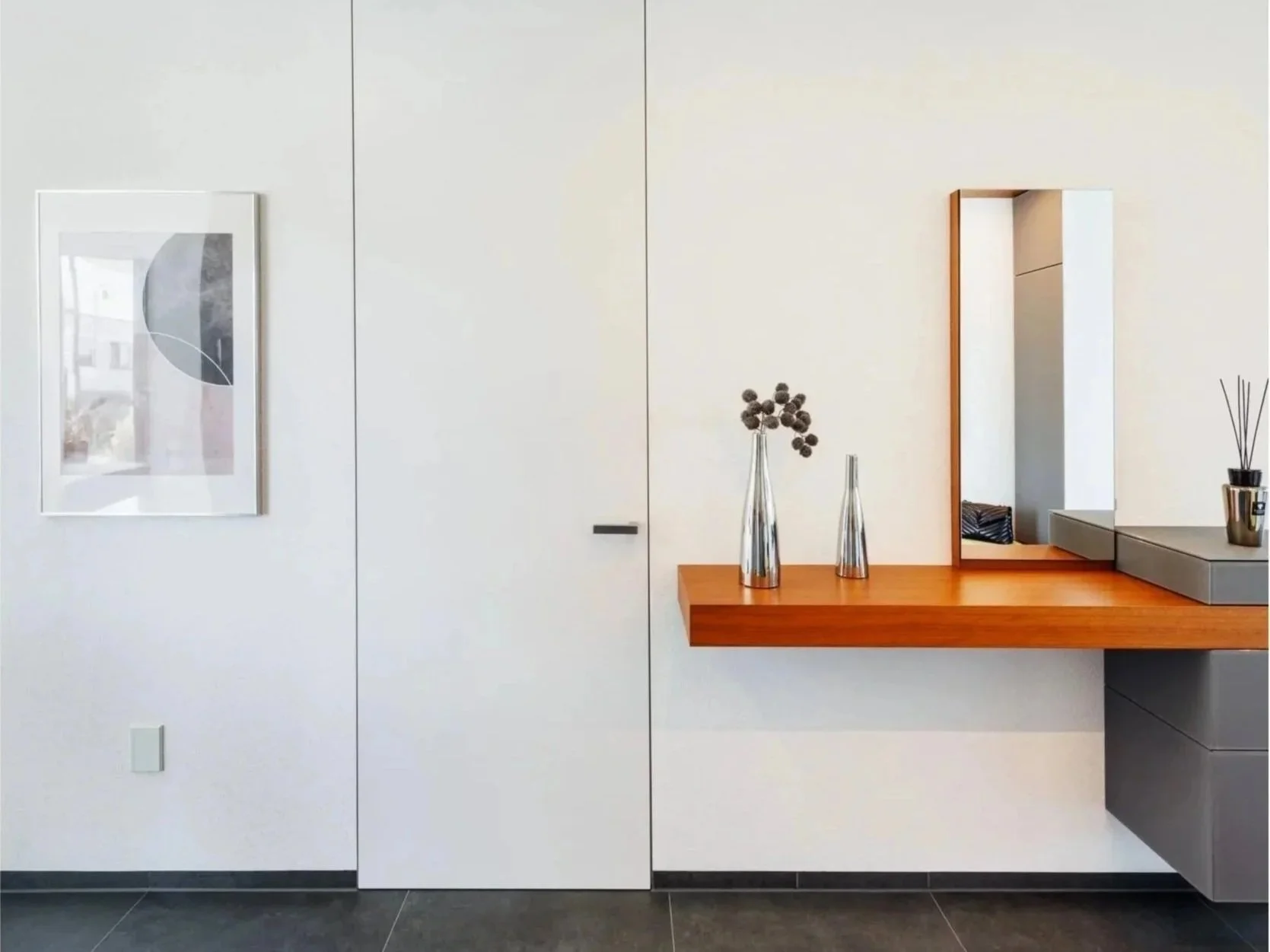 Modernes Wohnzimmer mit weißen Wänden, Wandbild, Holzkonsole, zwei Vasen mit getrockneten Blumen, Wandspiegel.