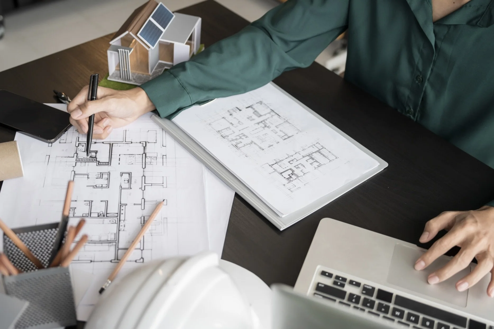 Schreibtisch sitzt Frau mit grüner Bluse erstellt Grundriss