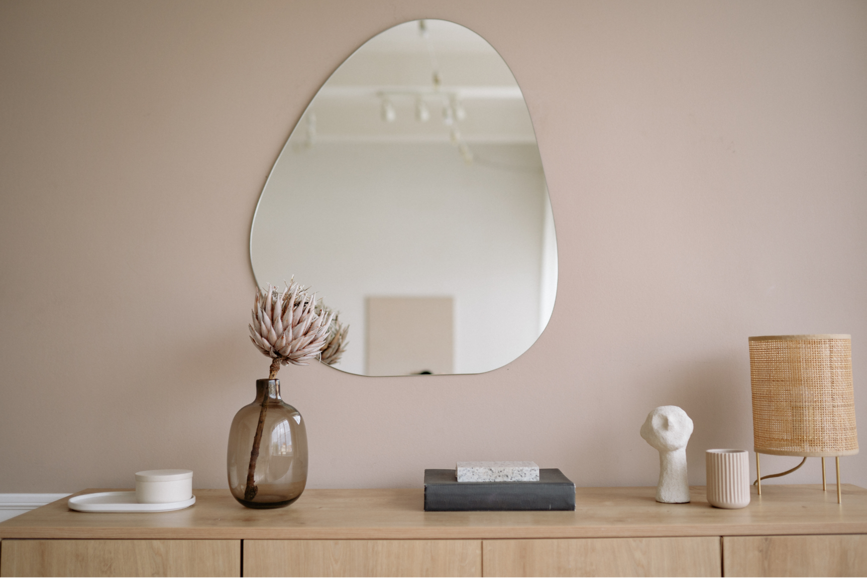 Rosa Wand mit Spiegel und darunter Sidboard, Lame und Vase