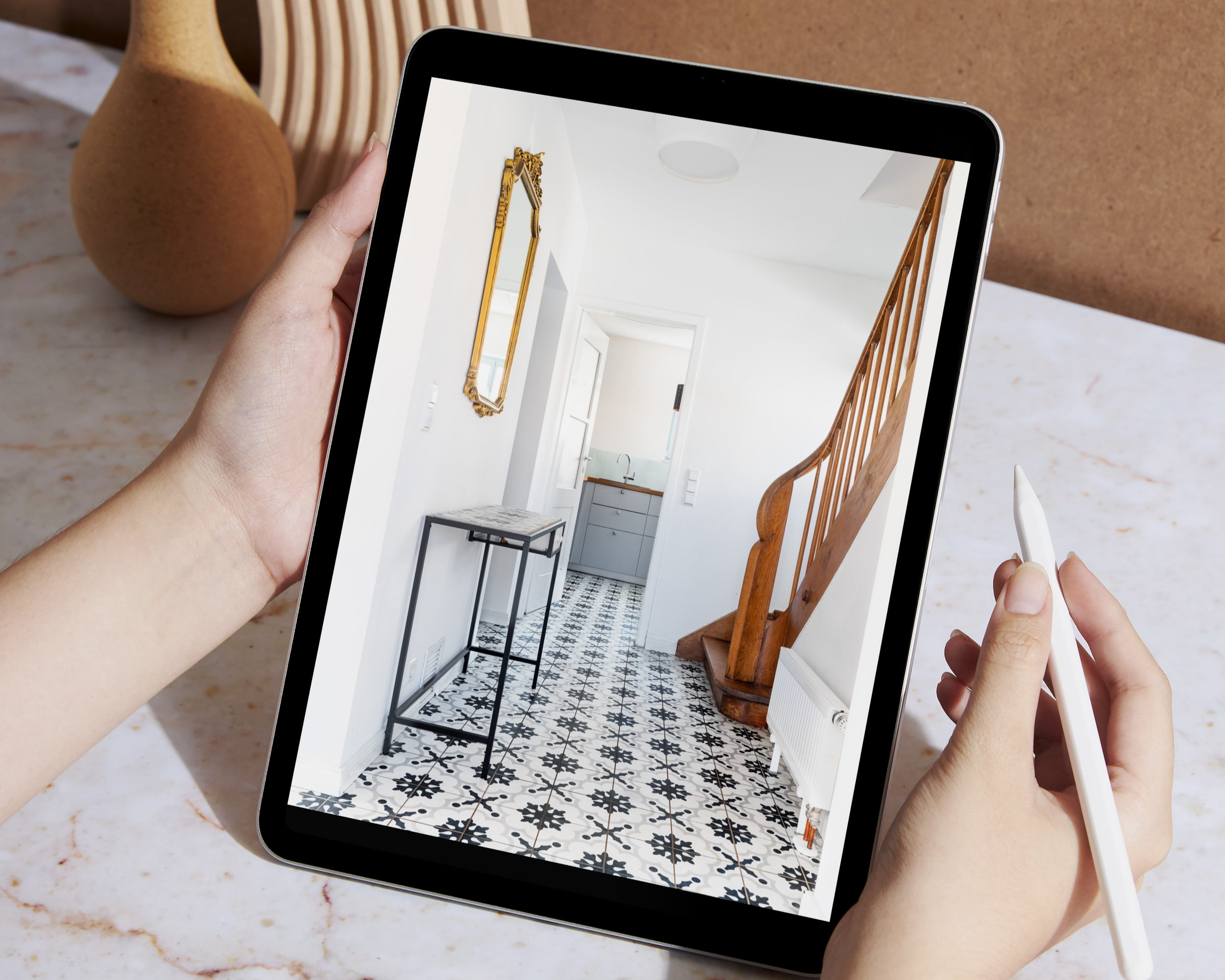 Ein Tablet zeigt ein Bild eines Flurs mit weißer Wand, Holztreppe, einer kleinen Konsole und Fliesenboden.
