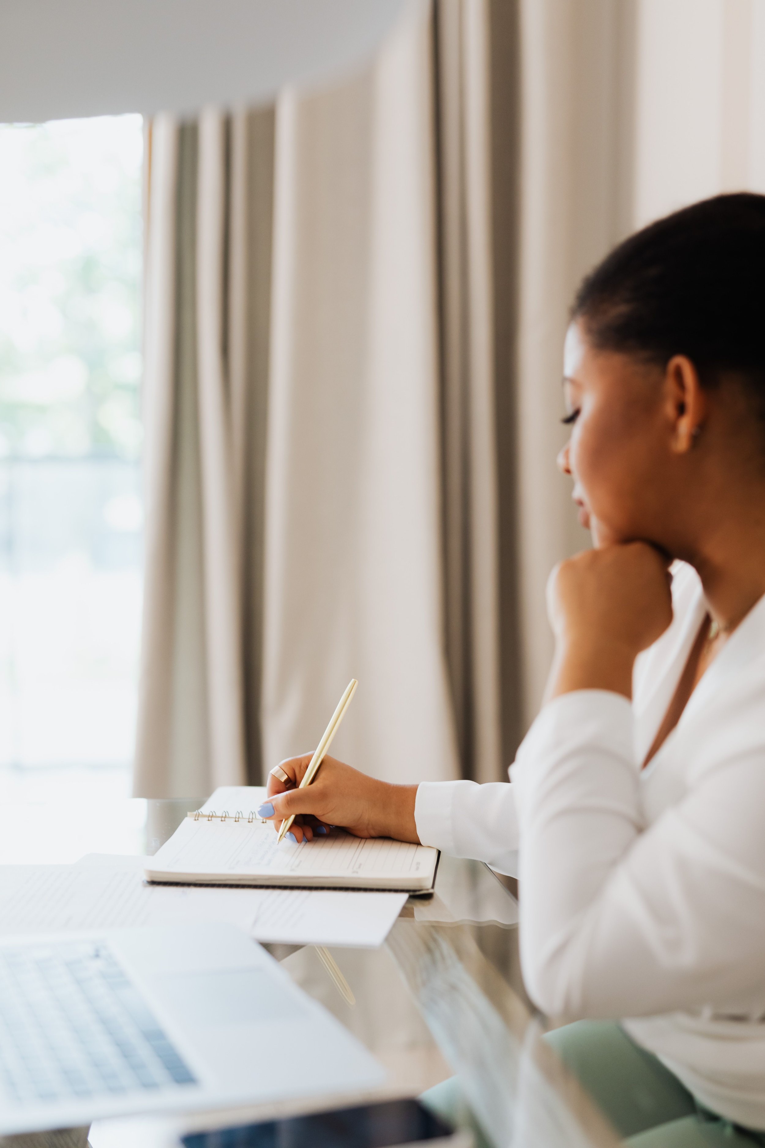 Therapist journaling next to a laptop with budget notes