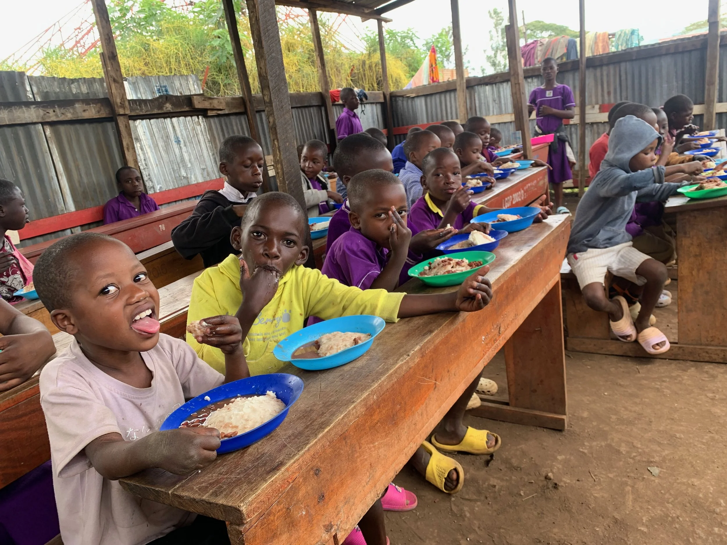 Children in their former eating structure eating their midday meal.