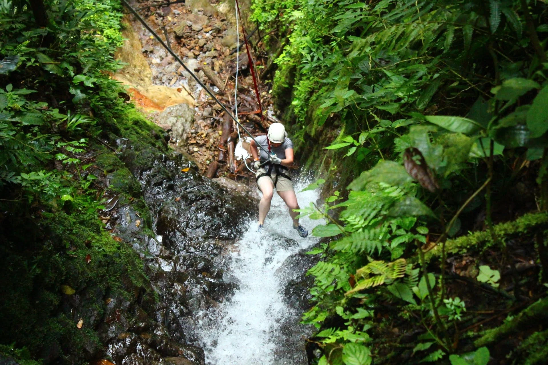 Woman canyoning down waterfall La Fortuna Costa Rica rainforest