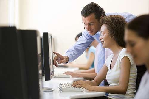 Teacher assisting student on computer in classroom setting