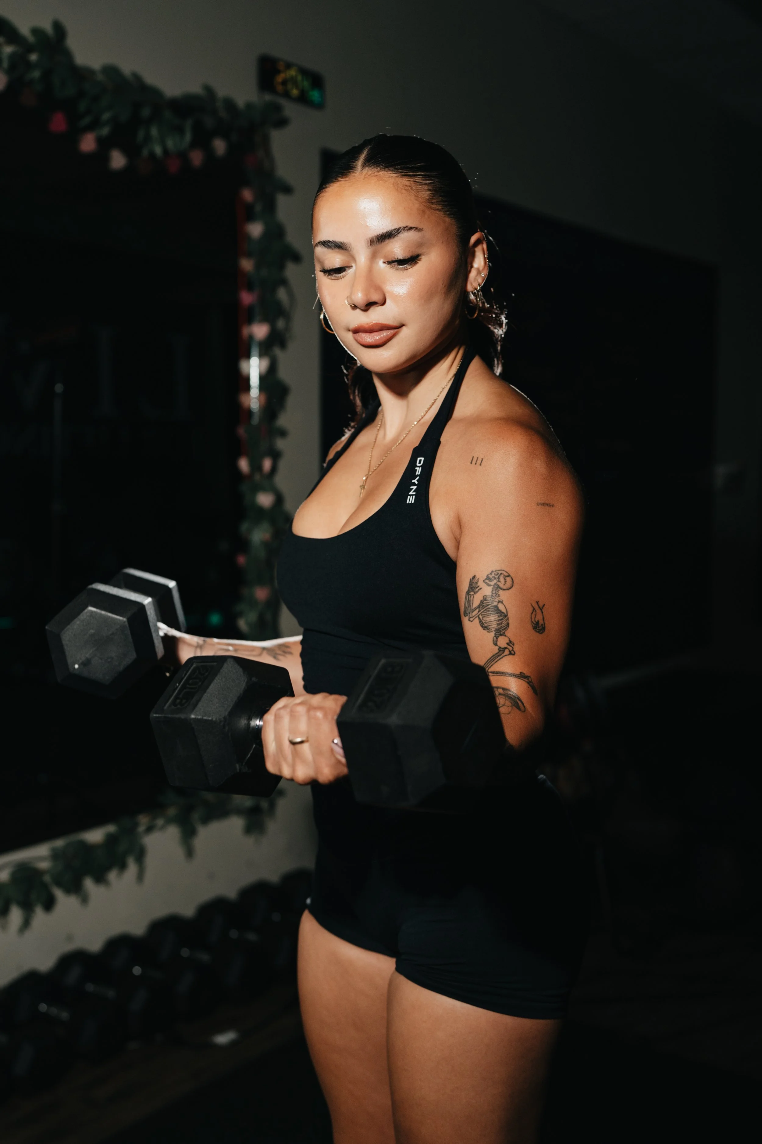 Young woman in athletic wear at gym, leaning on a barbell.