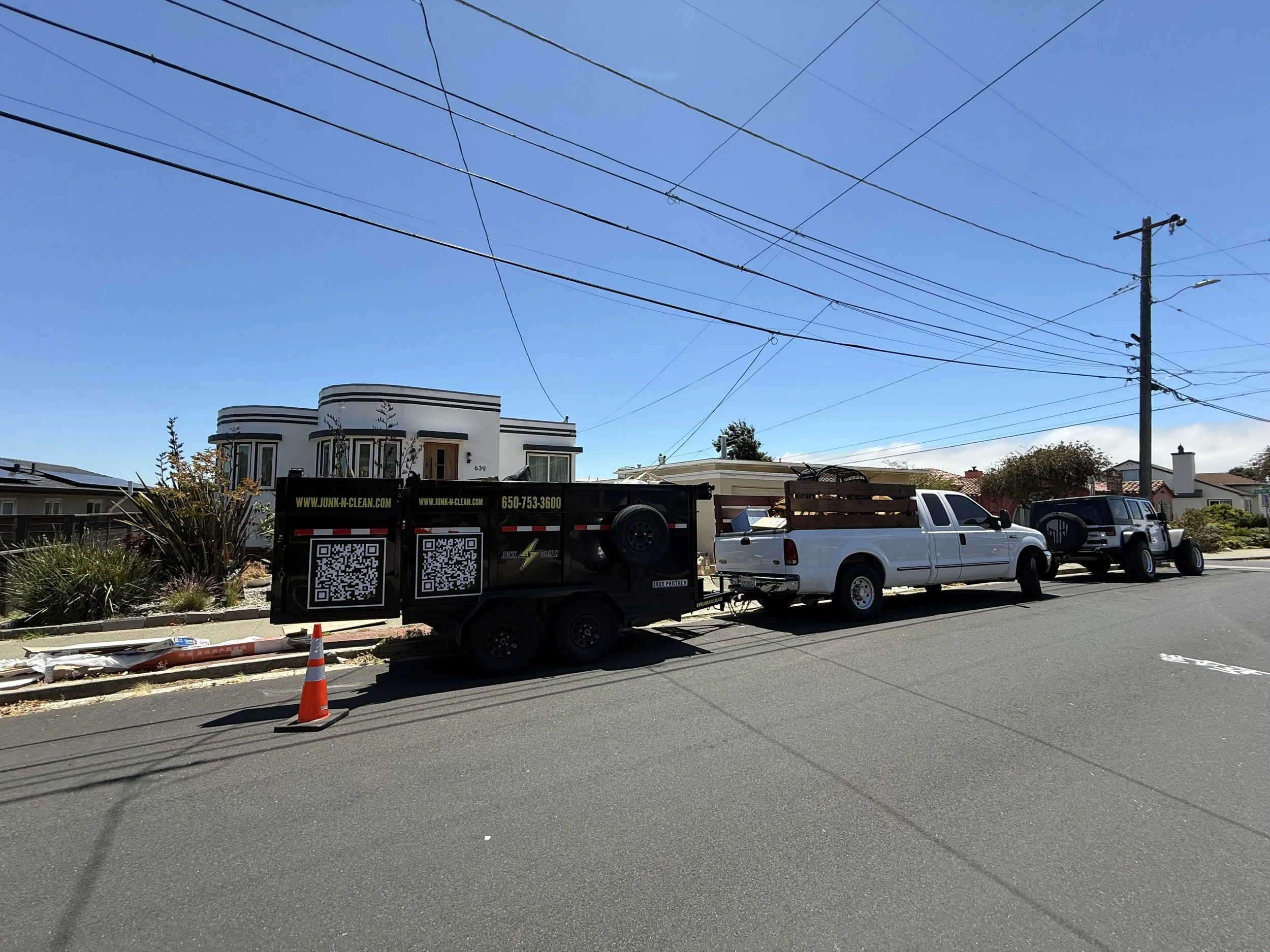 Street scene with a white house, utility poles, and a truck parked on the street during daytime.