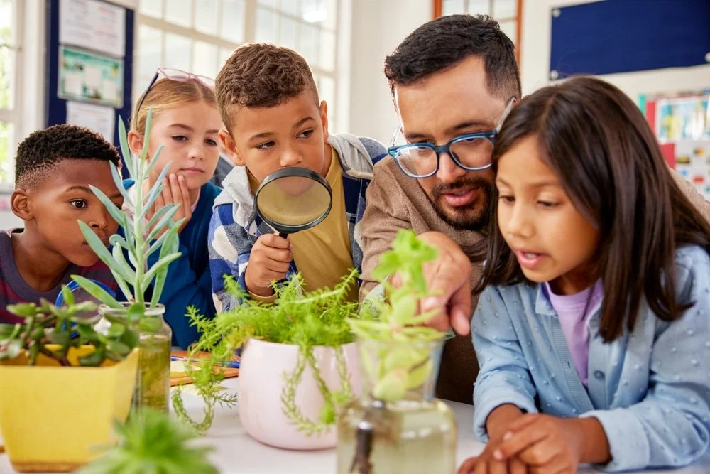 A teacher showing children plants in a classroom during a science lesson.