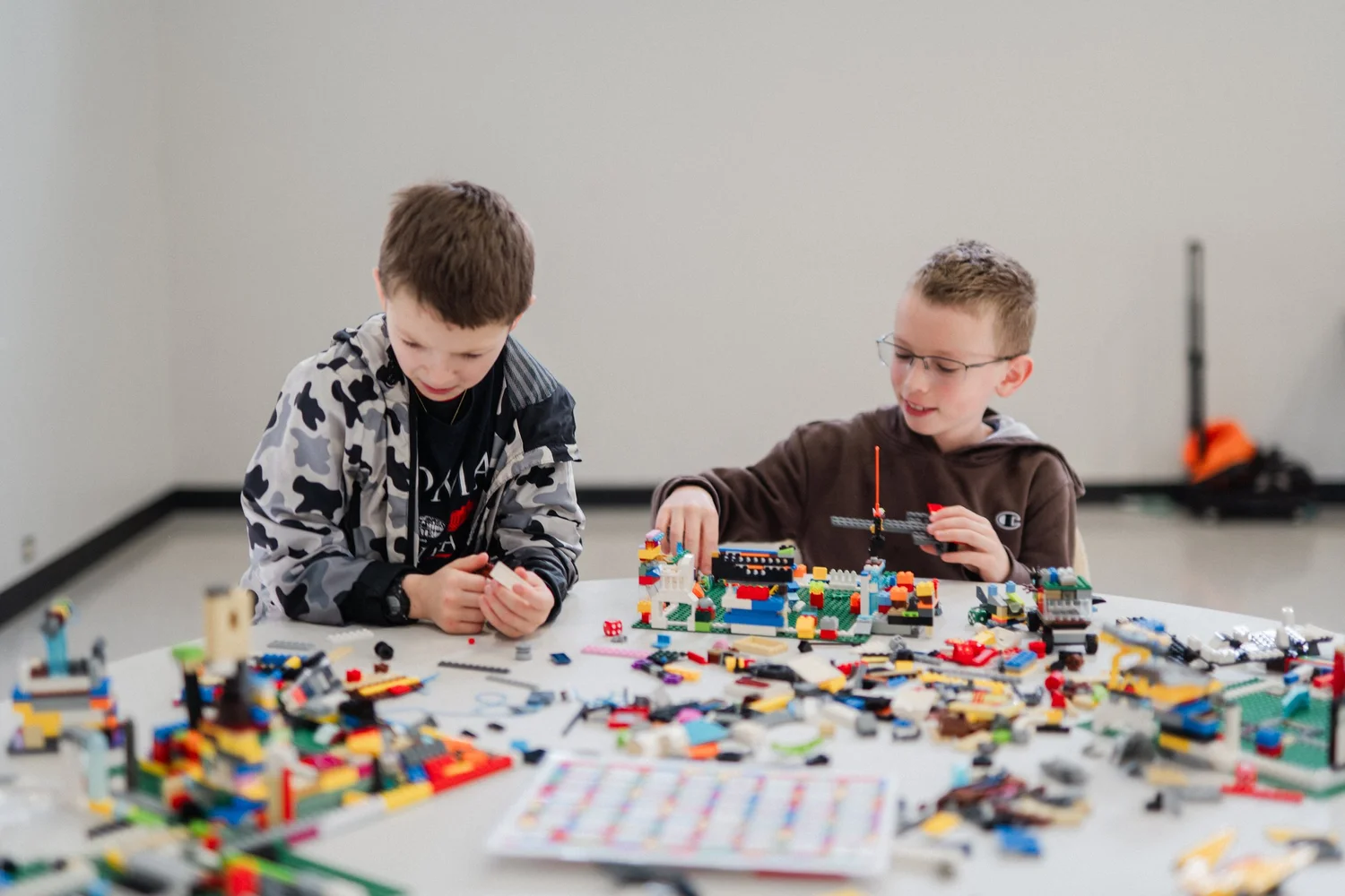 Two kids building a LEGO machine together at a party