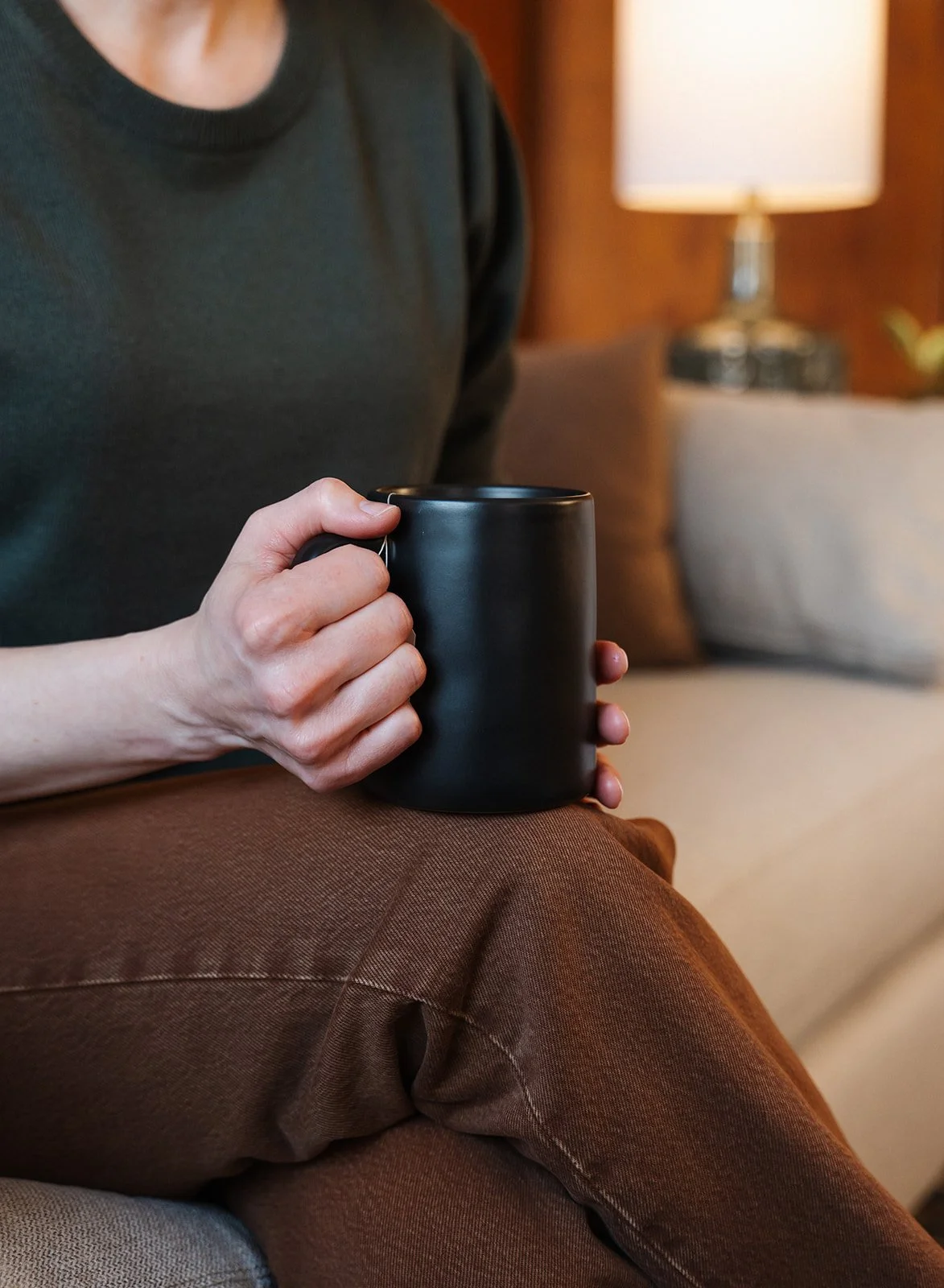 Woman in black shirt holding a black cup of tea