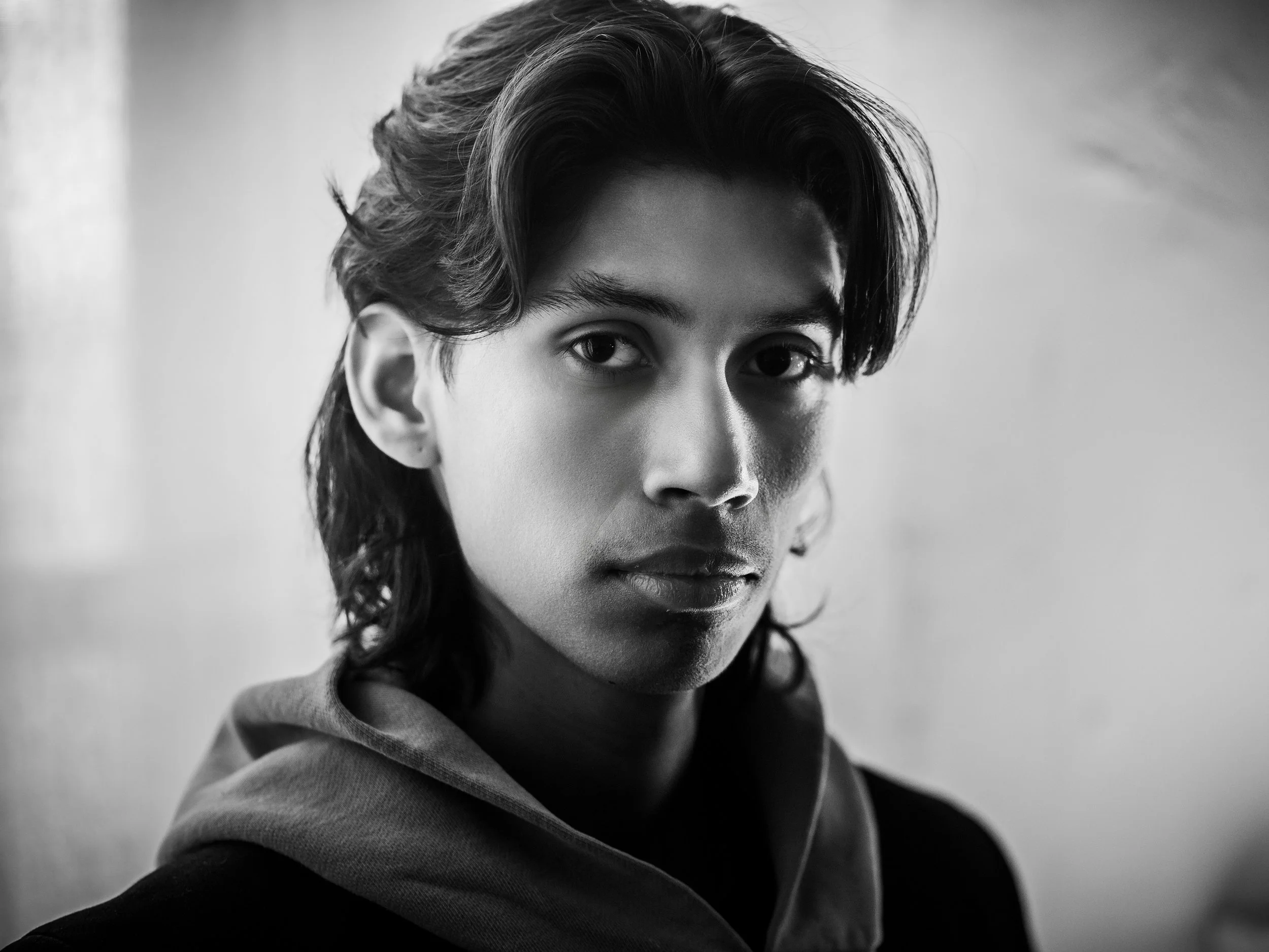 Black and white portrait of a person with long hair and a serious expression.