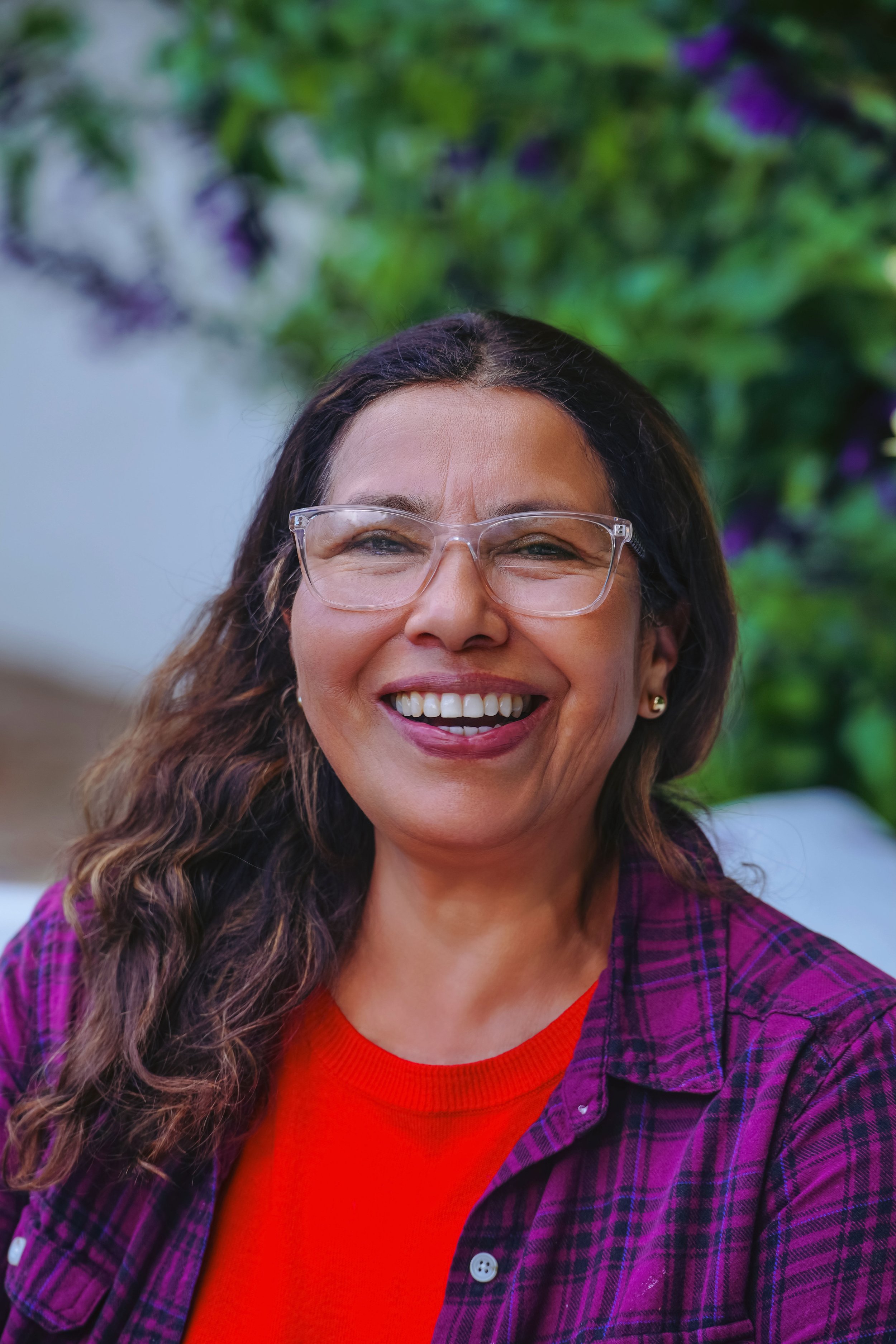 Smiling woman wearing glasses and a purple plaid shirt outdoors