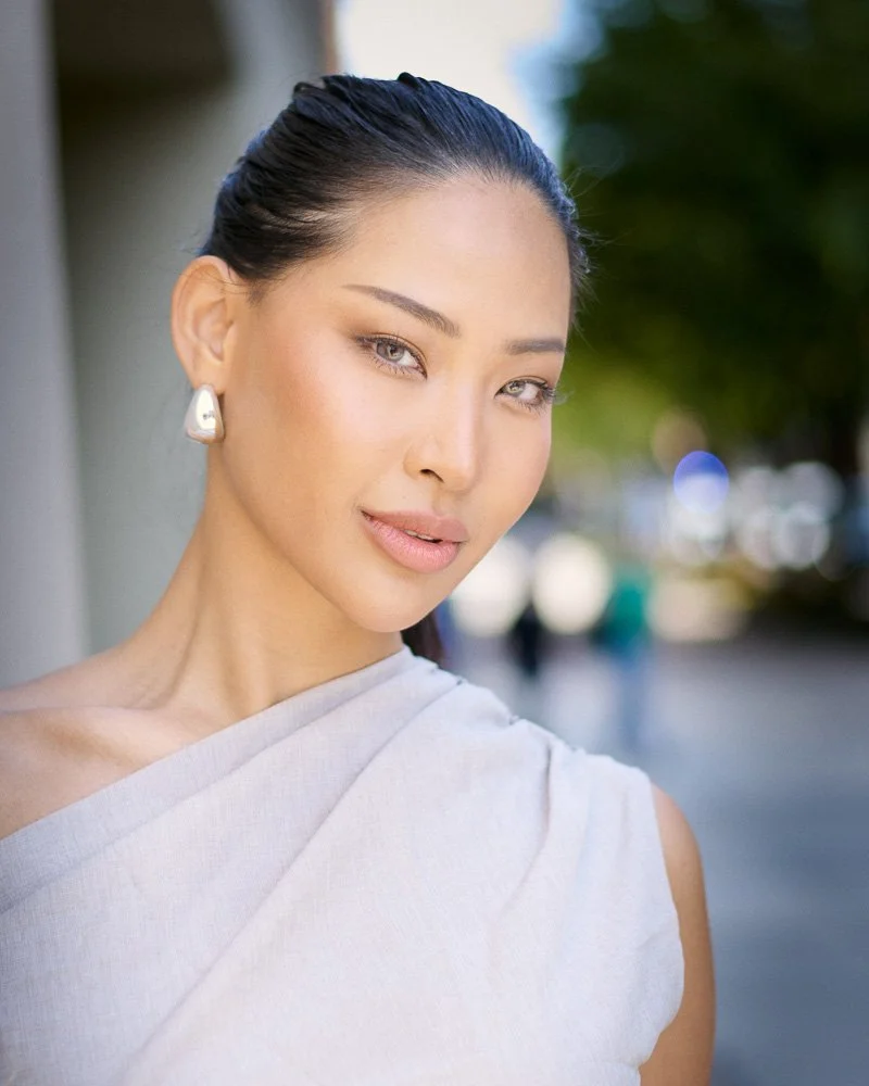 Close-up natural-light portrait of a woman wearing a one-shoulder top in New York City.